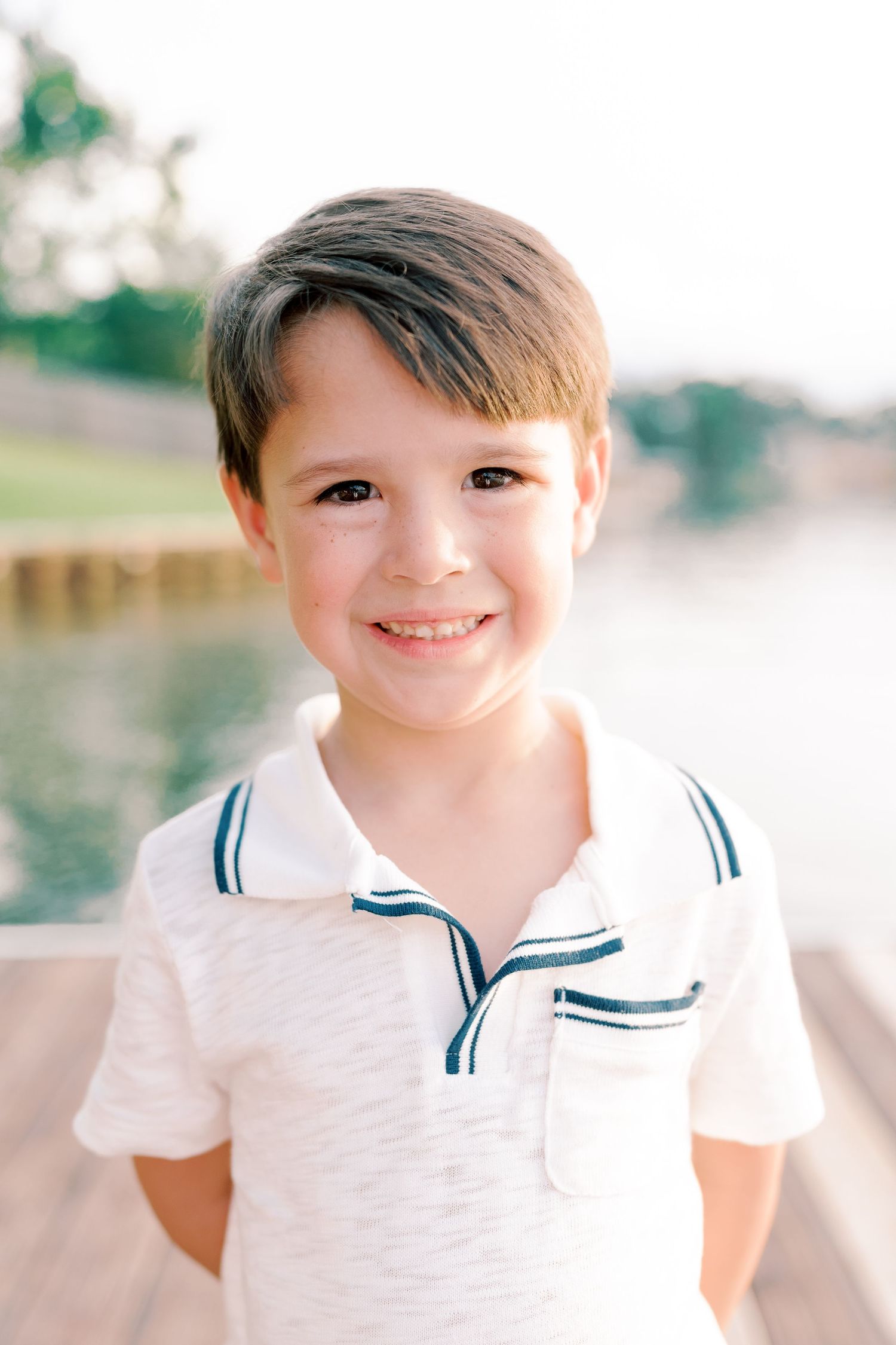 Close-up portrait of child in white sailor-style collar shirt on dock.