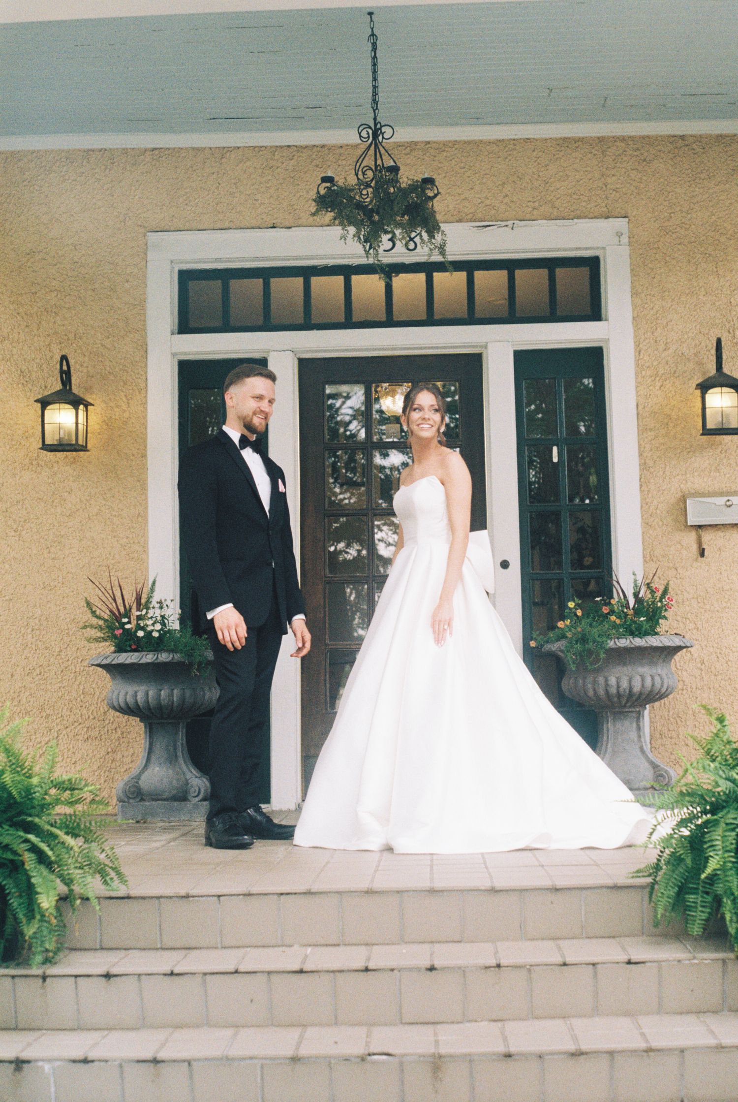 Wedding couple sharing moments on a front porch with classic architecture.