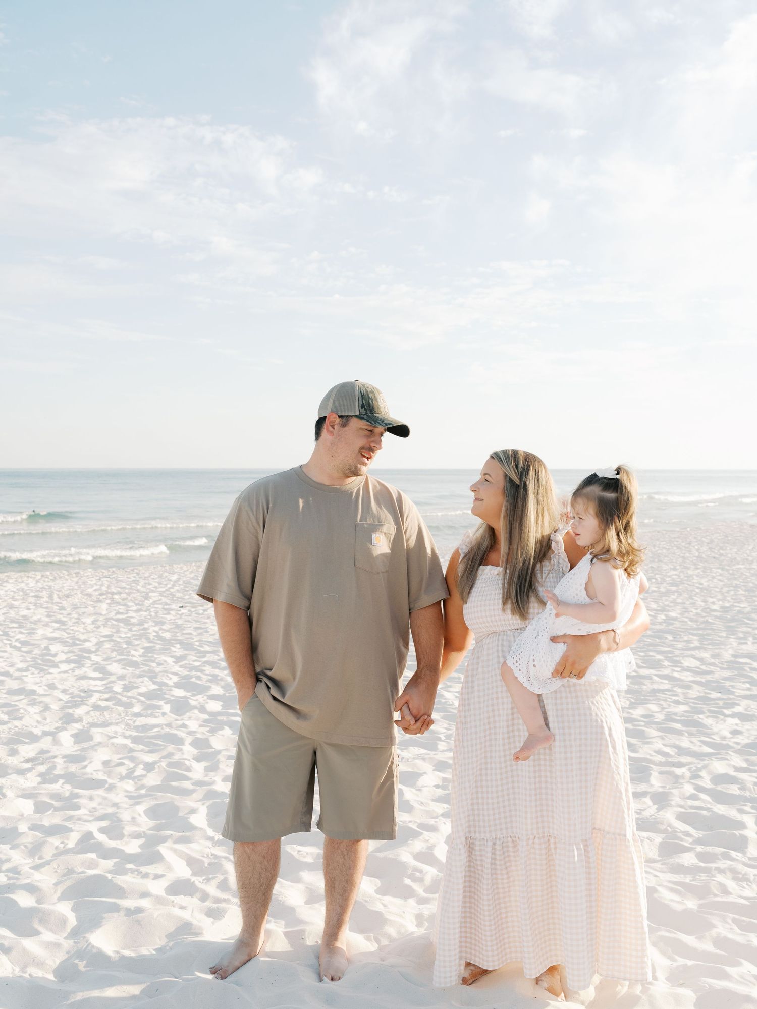 Group strolling barefoot along a white sandy beach with beachfront condos visible in the distance.