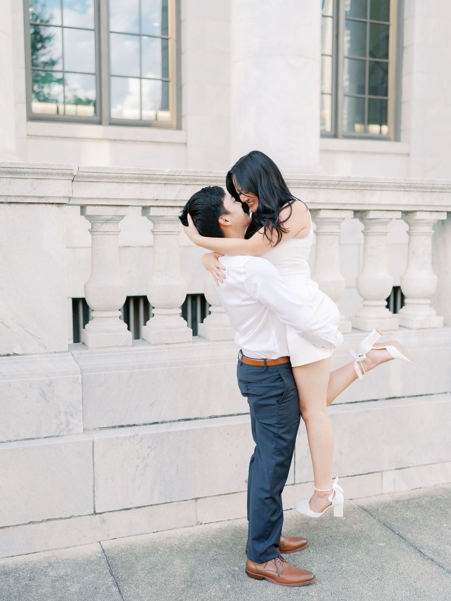 Romantic dip pose on marble steps with classic white architecture backdrop.