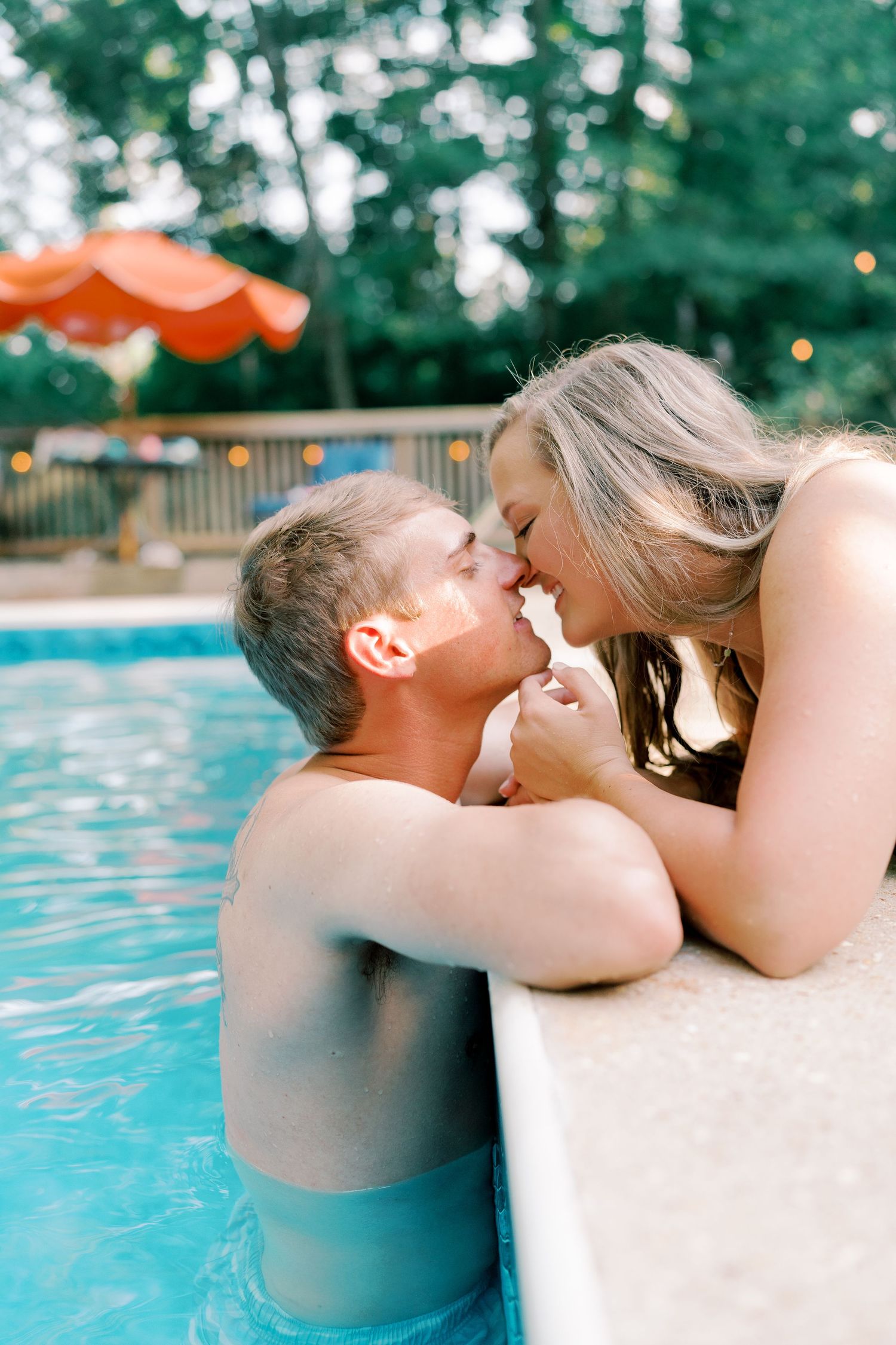 Romantic poolside moment between a couple leaning in close together.