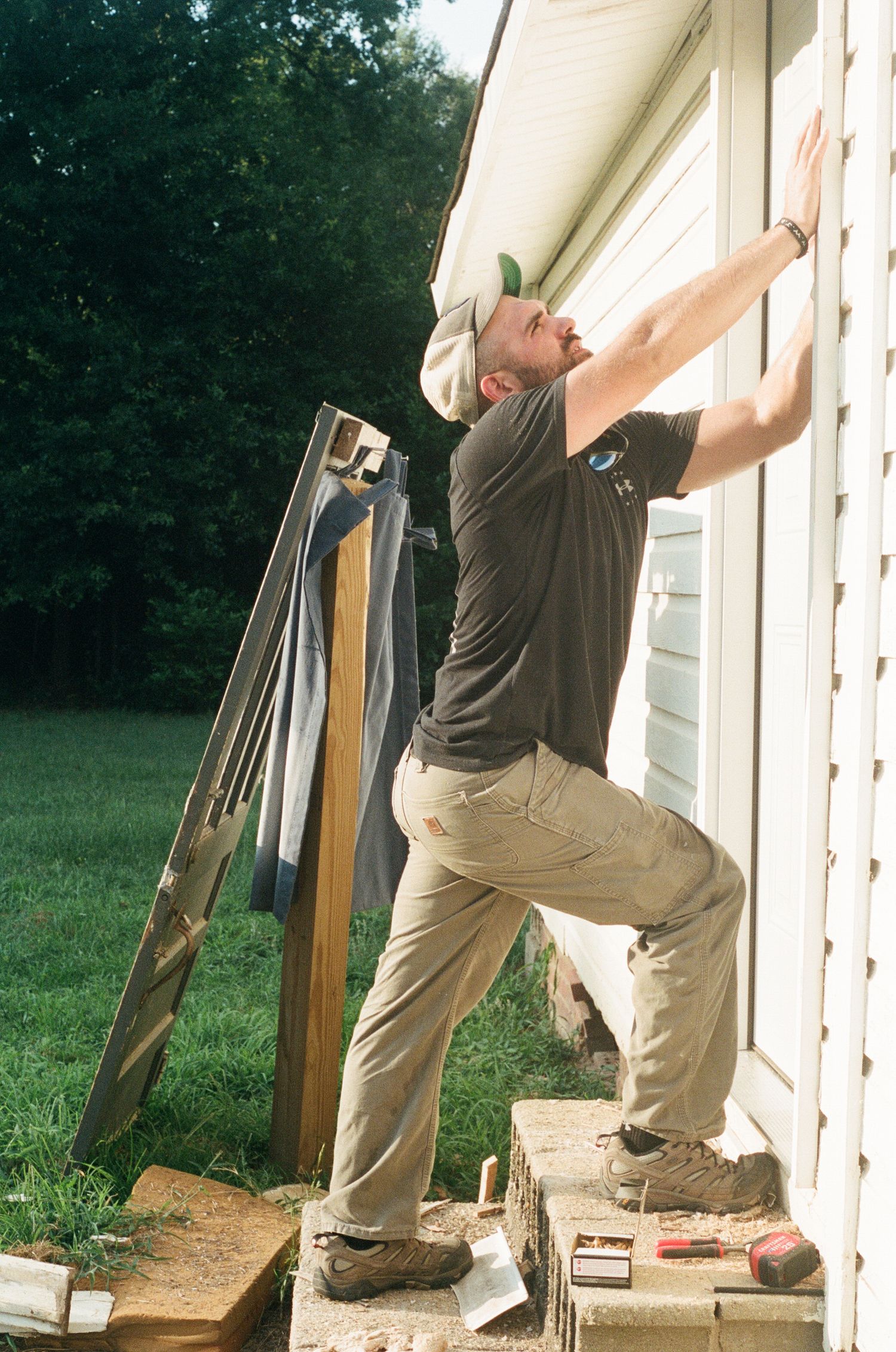 Sequence showing someone installing or repairing white siding on a house exterior.