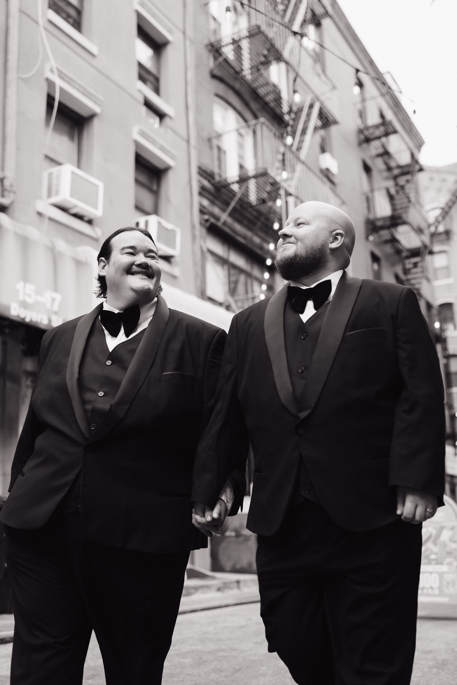 Group wearing black formal attire laughing together on an urban street.