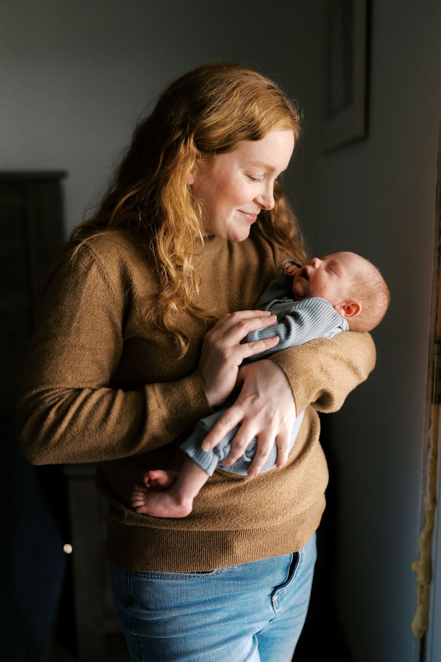 Gentle moments captured between parent and newborn in natural window light.