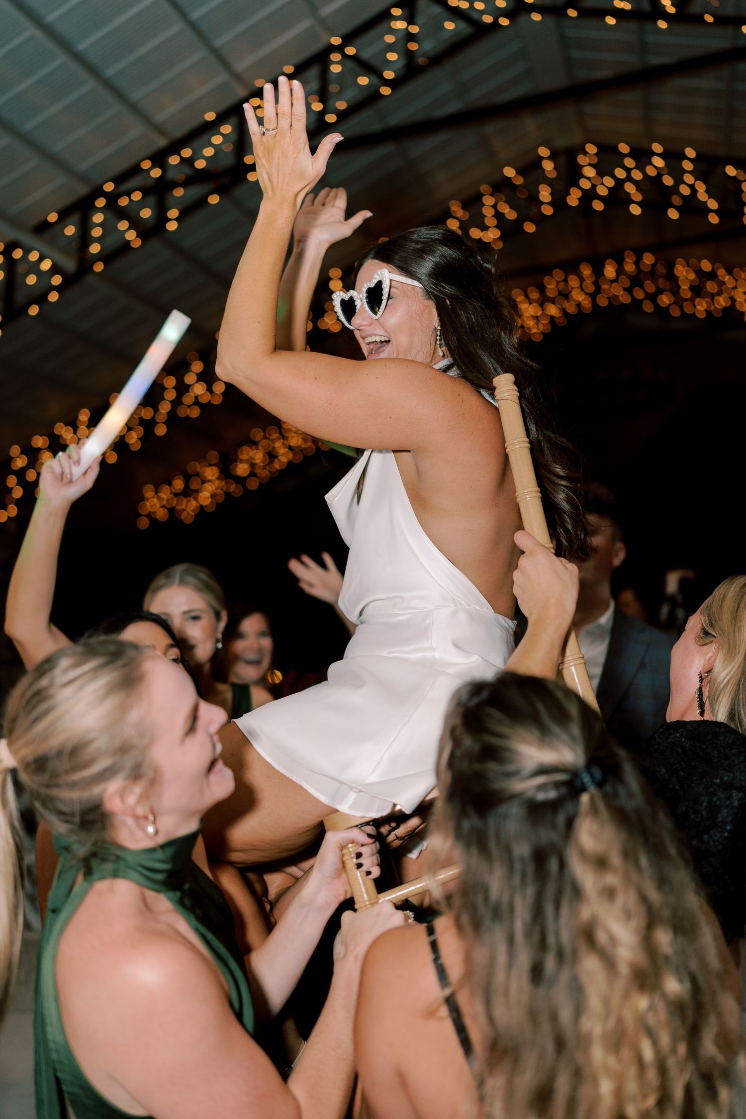 Wedding celebration with guests dancing and lifting someone above the crowd.