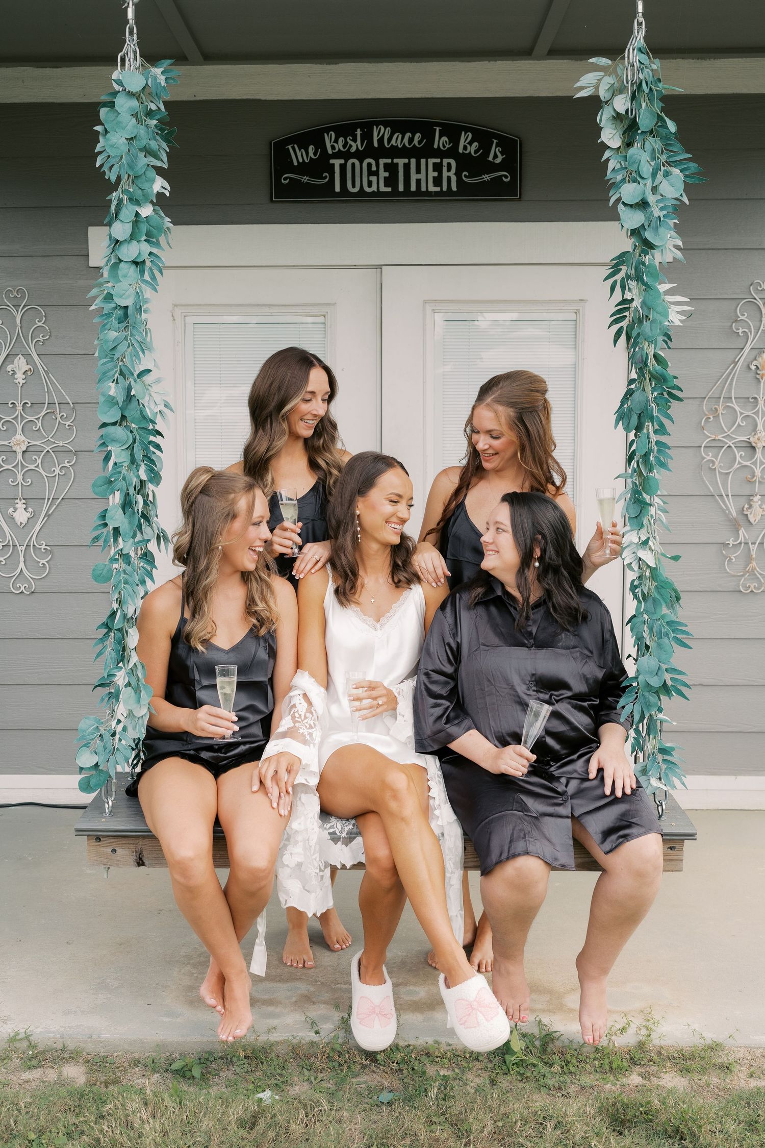 Bridesmaids in robes sitting on porch with turquoise decorations.