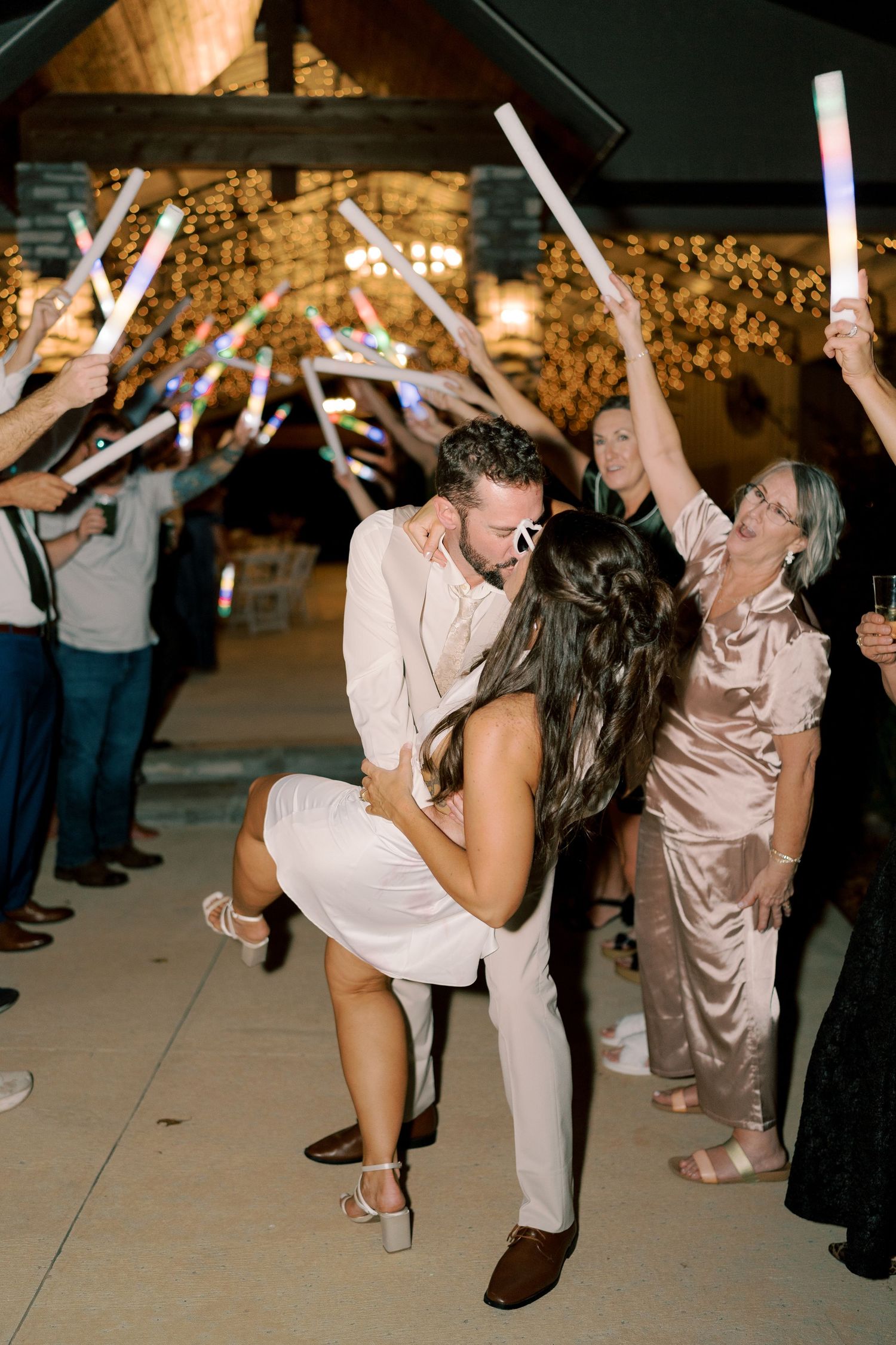 Couples dance together during a festive wedding reception with light beams overhead.