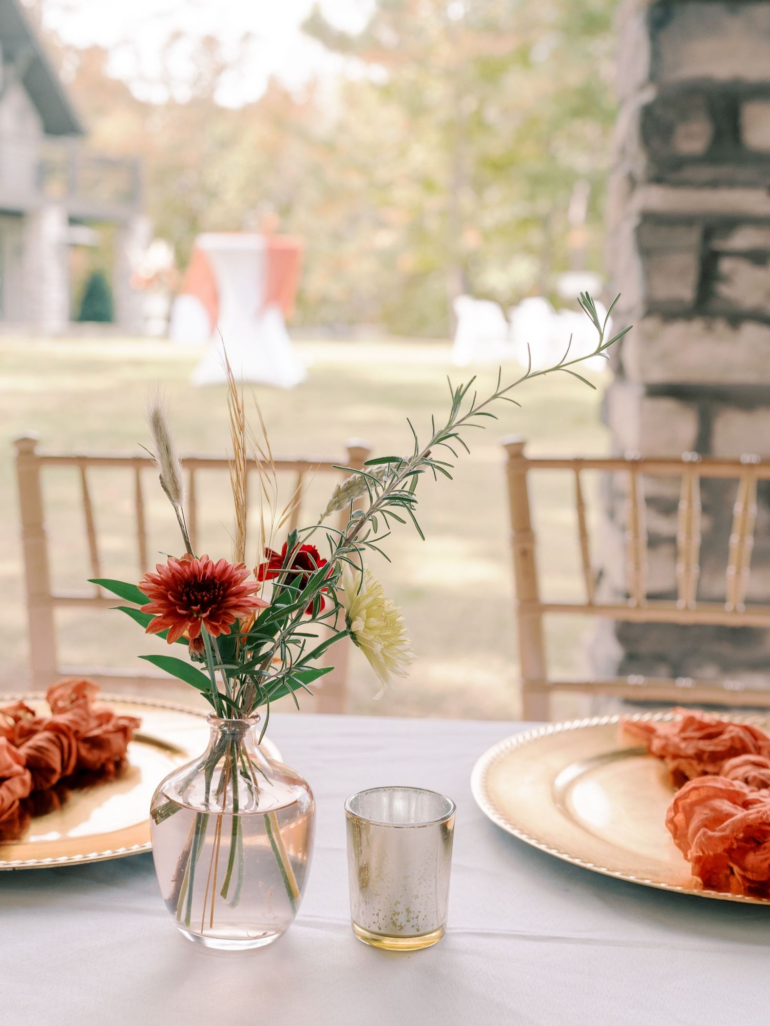 Wedding table settings with copper chargers and delicate floral centerpieces.
