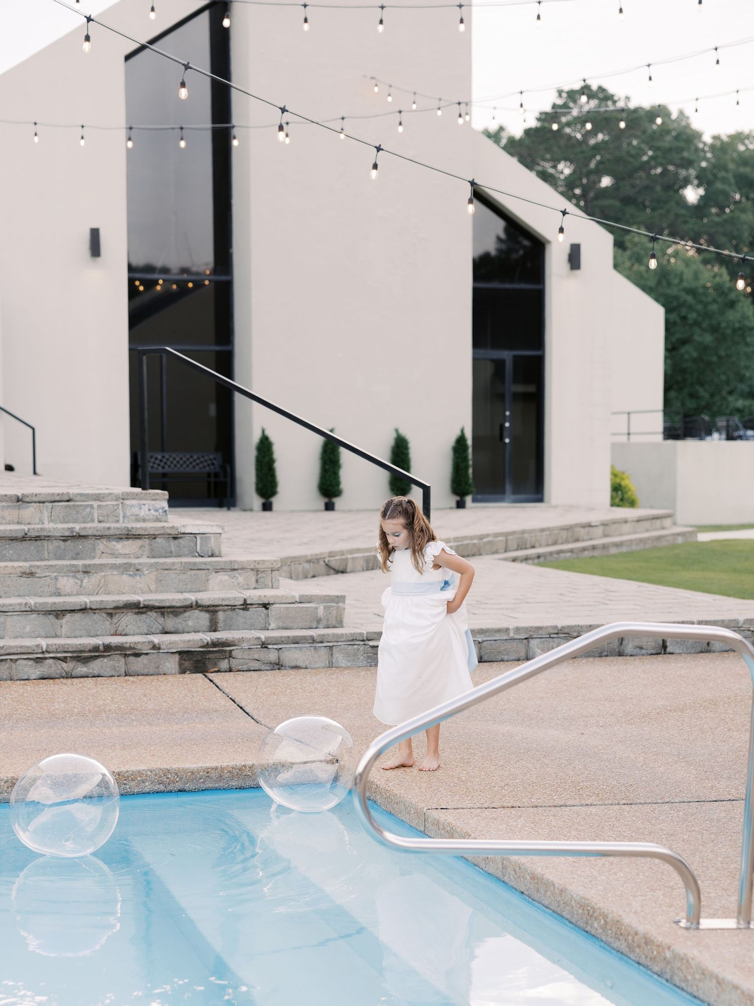 Wedding venue with modern architecture, string lights, and pool featuring large bubble decorations.
