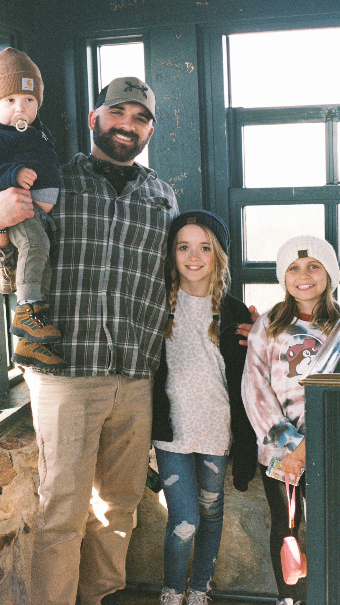 Group gathering in casual winter attire inside a rustic room.