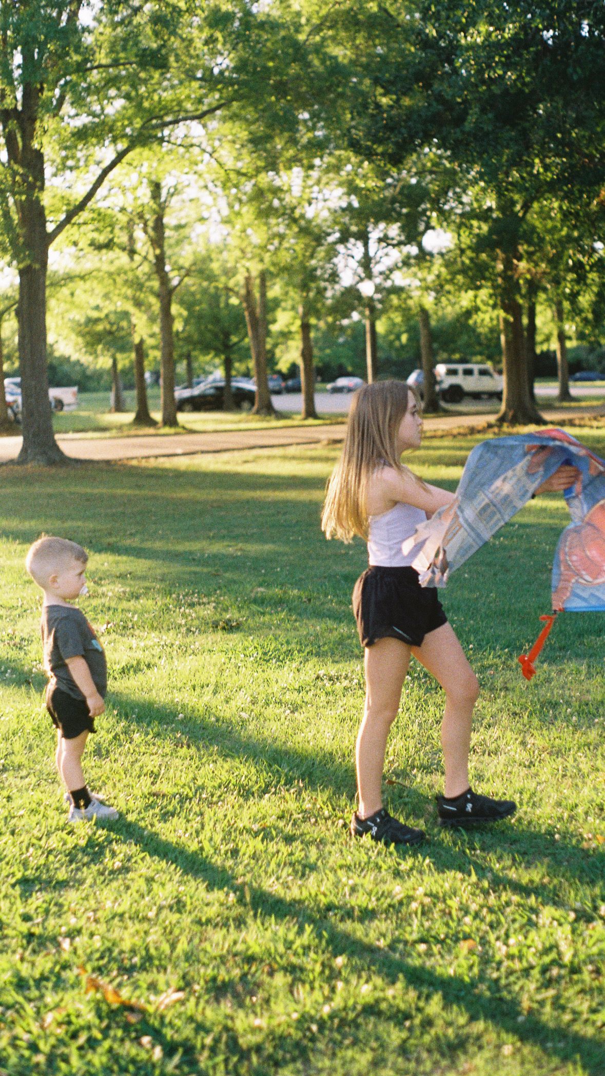 Children doing cartwheels on green grass in a sunny park.