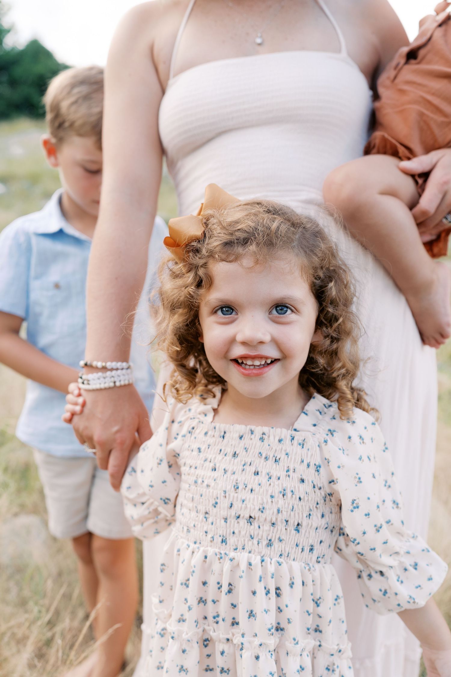 A close-up portrait shows a smiling child in a floral dress outdoors.