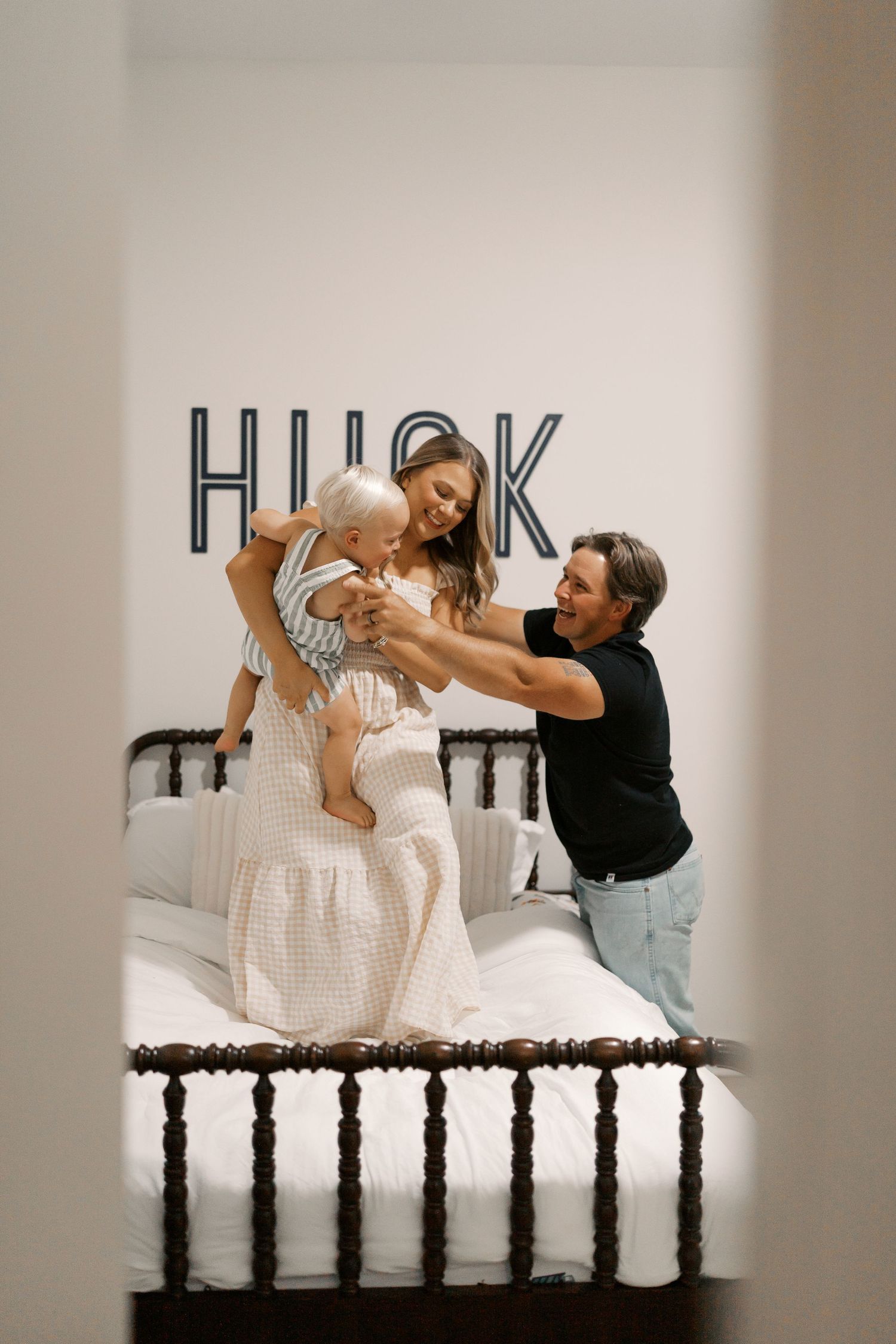 Playful interactions on a wooden bed with spindle headboard in a bright room.