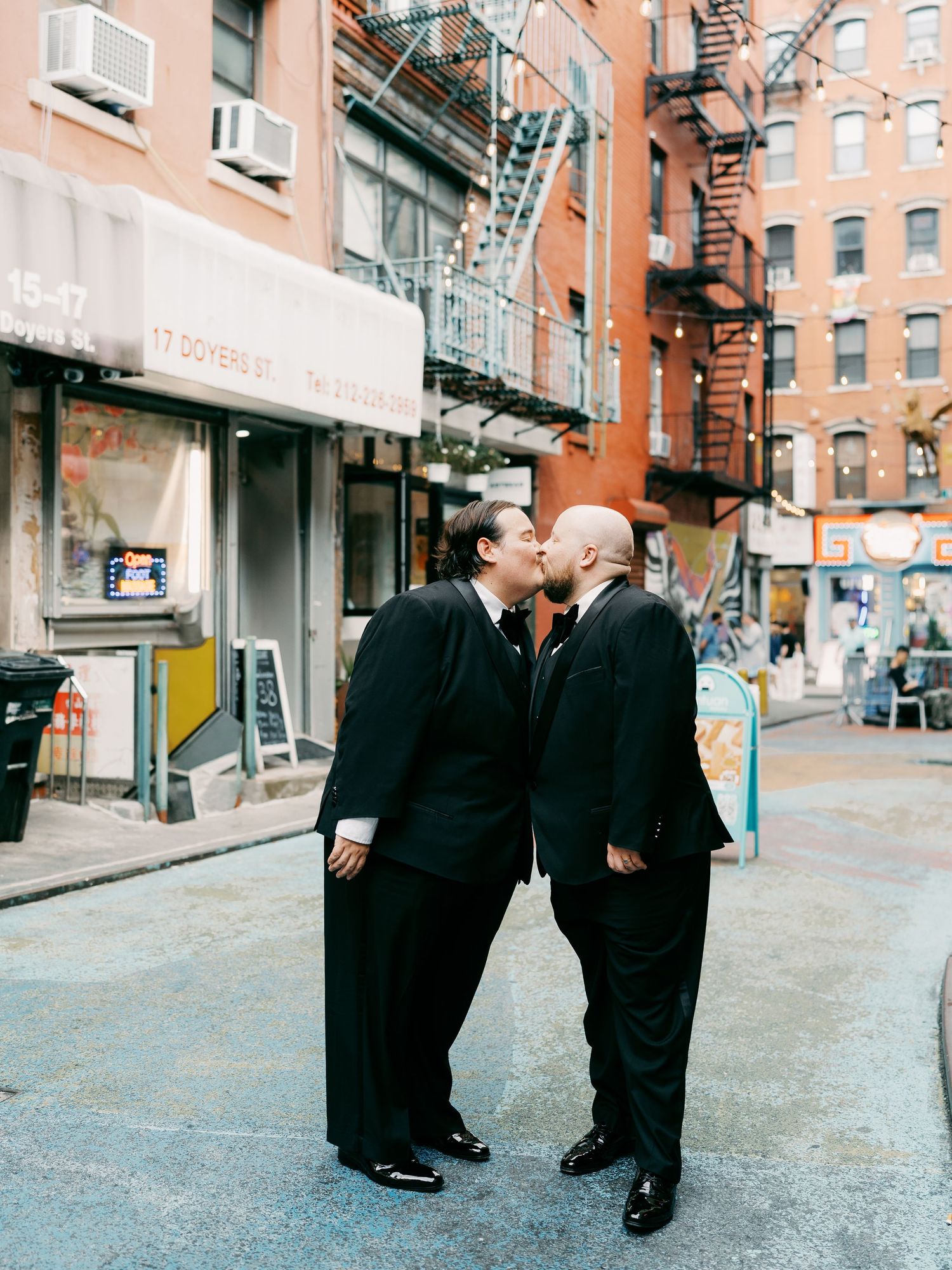 People in formal black clothing walking down a city sidewalk.