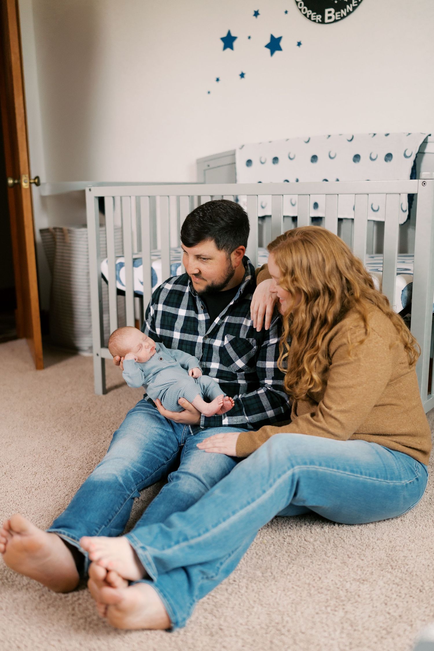 Family members relaxing together on beige carpet beneath blue star wall decorations.