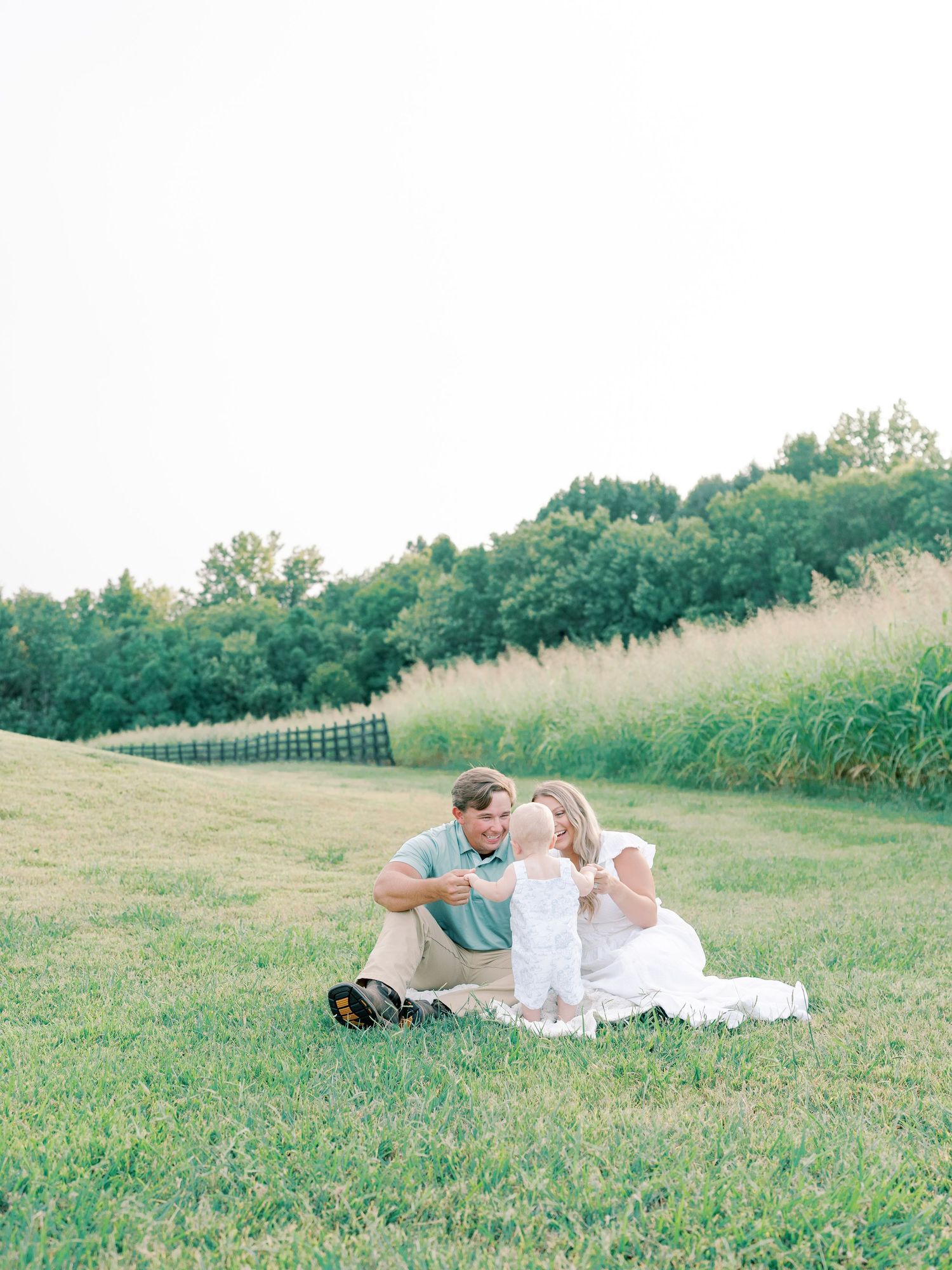 Family lying together on grass during golden hour outdoor photo session.