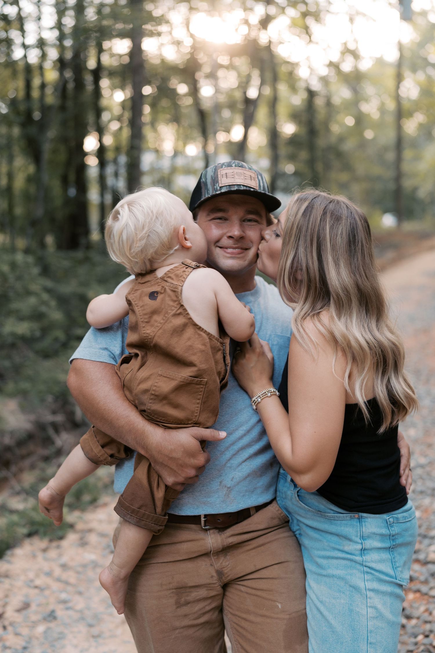 A loving family shares embraces and laughter on a sunlit forest trail.