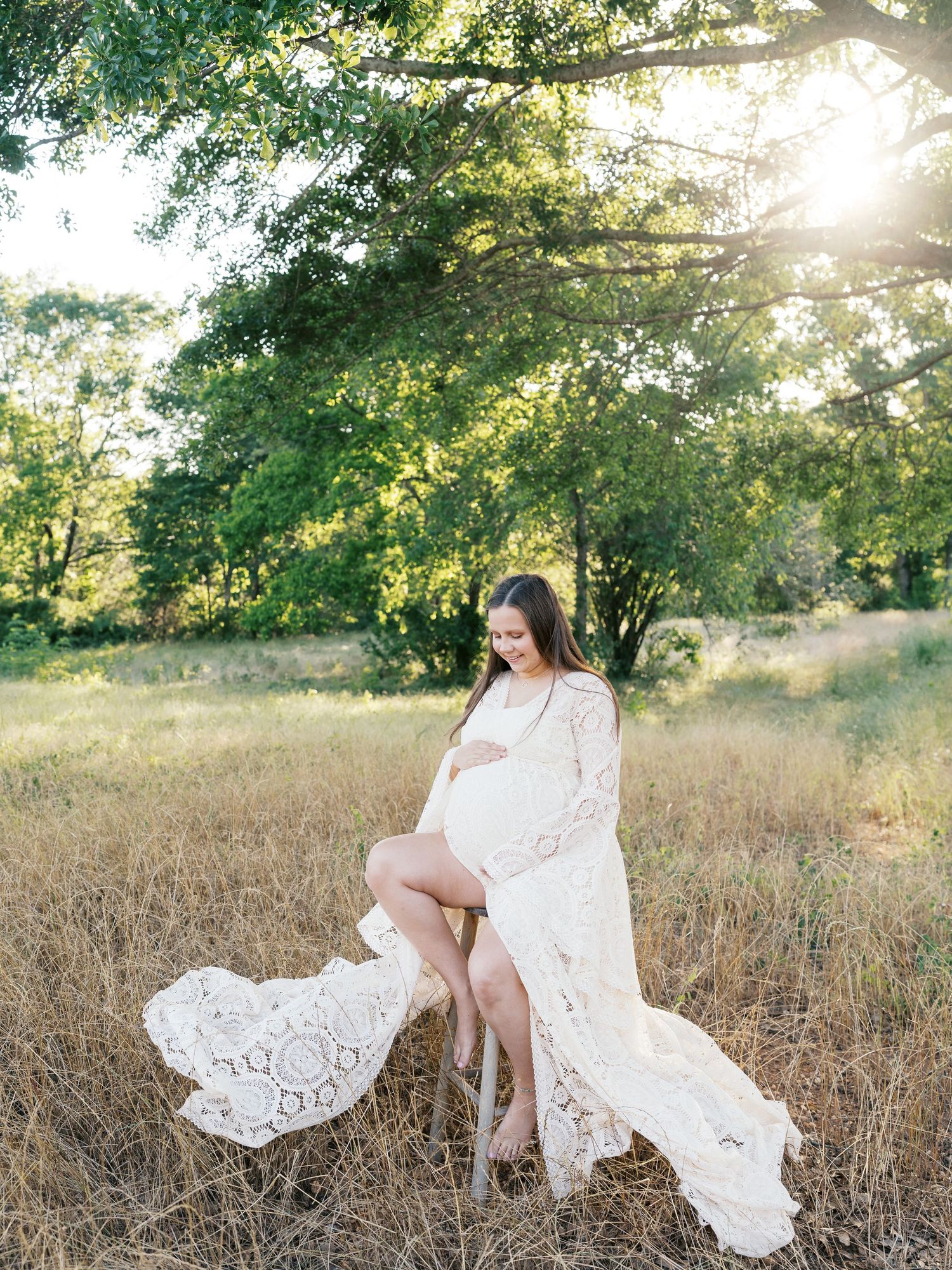 Ethereal white lace dress captured in motion against sun-kissed field.