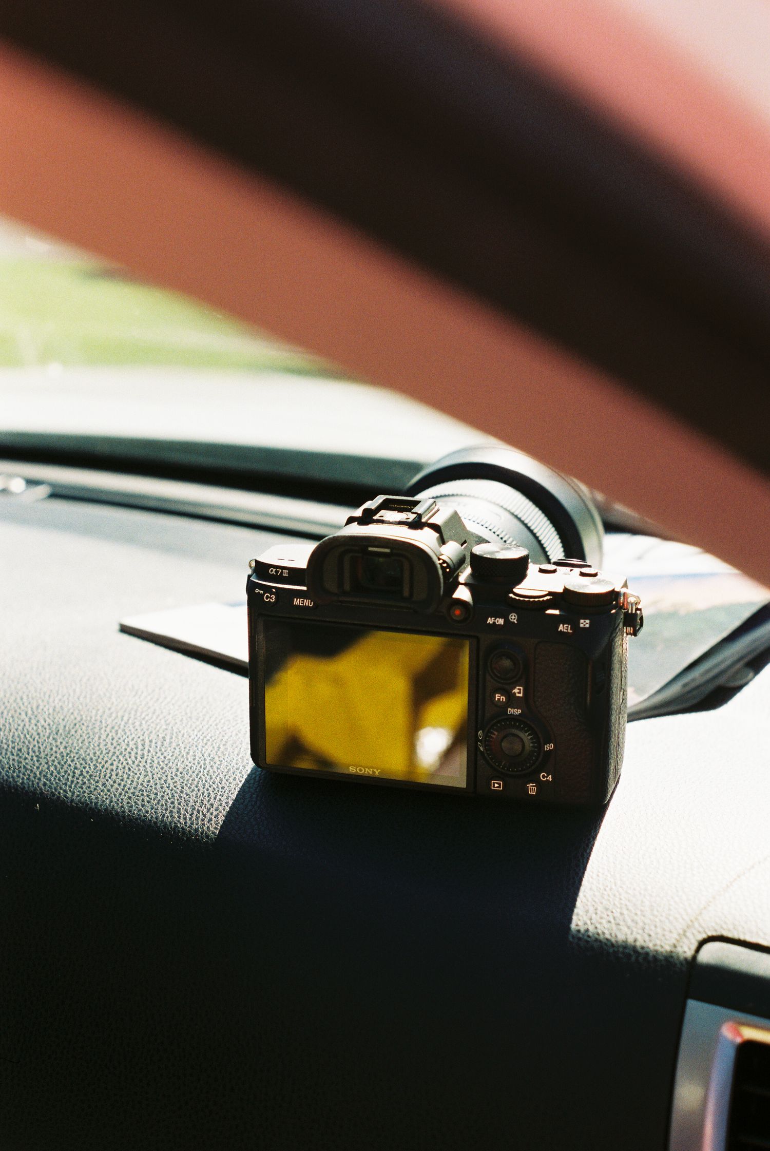 Digital camera resting on a car dashboard in natural sunlight.