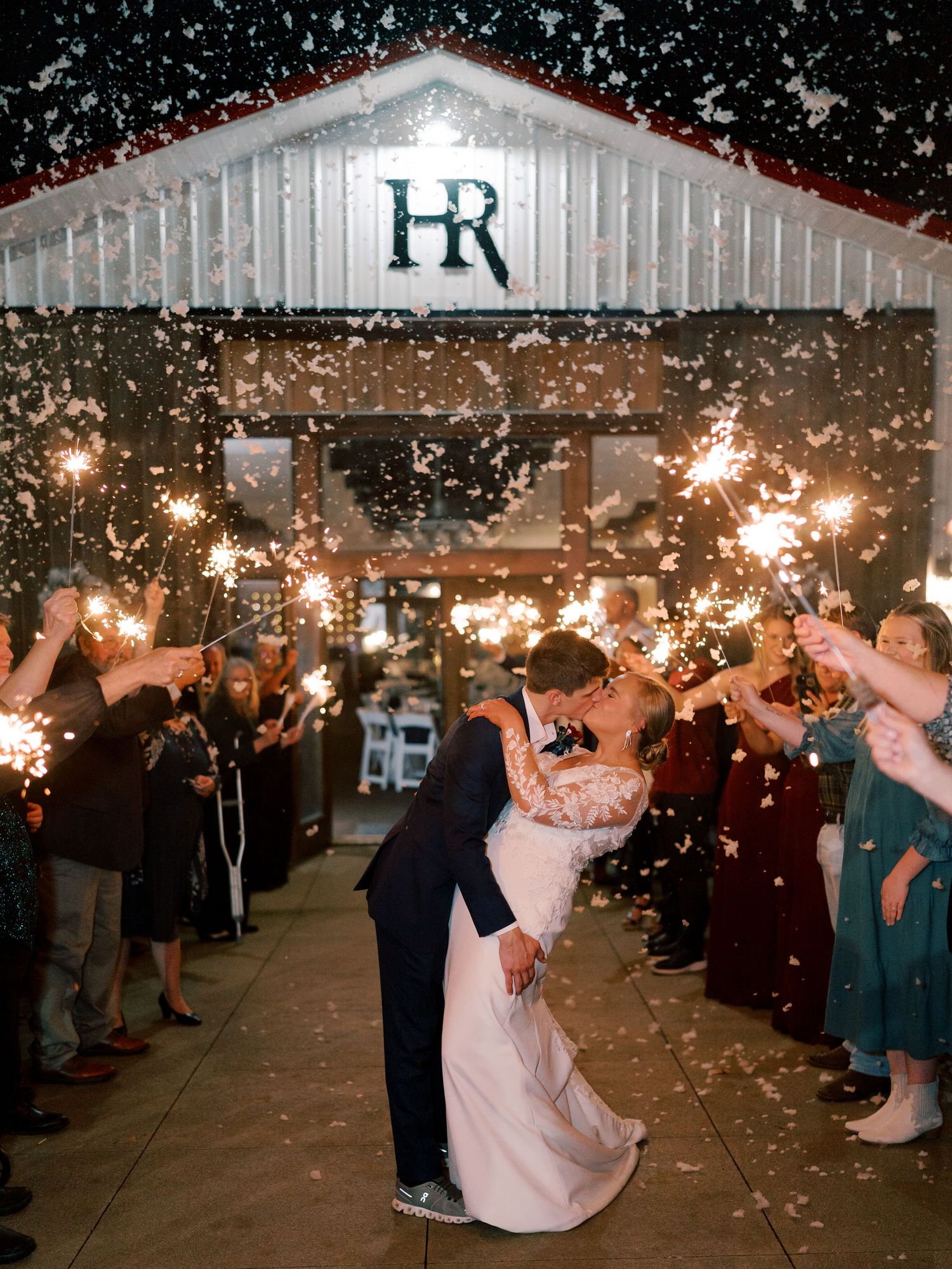 Newlyweds exit their wedding reception under a magical sparkler send-off with guests creating a glowing tunnel.