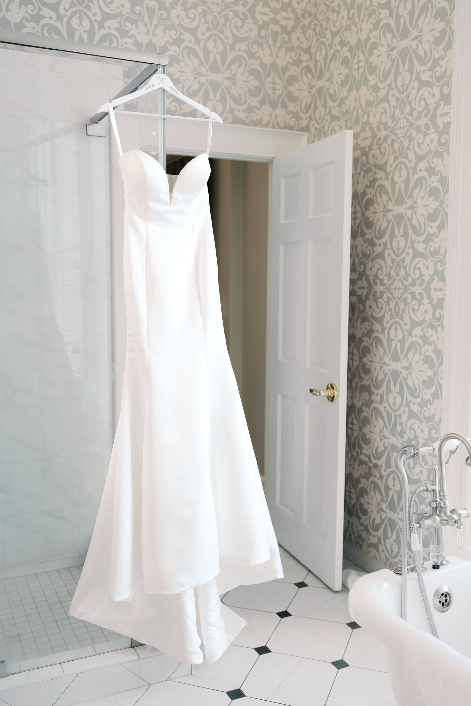White shower curtains and wallpaper with damask pattern in an elegant bathroom setting.
