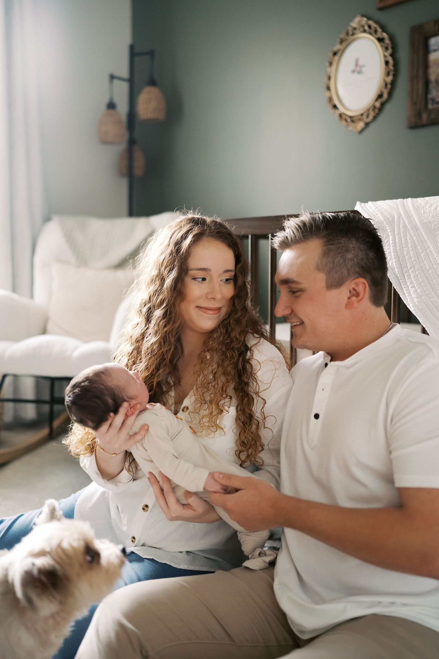 Sweet family bonding moment on white carpet with their dog nearby in modern nursery setting.