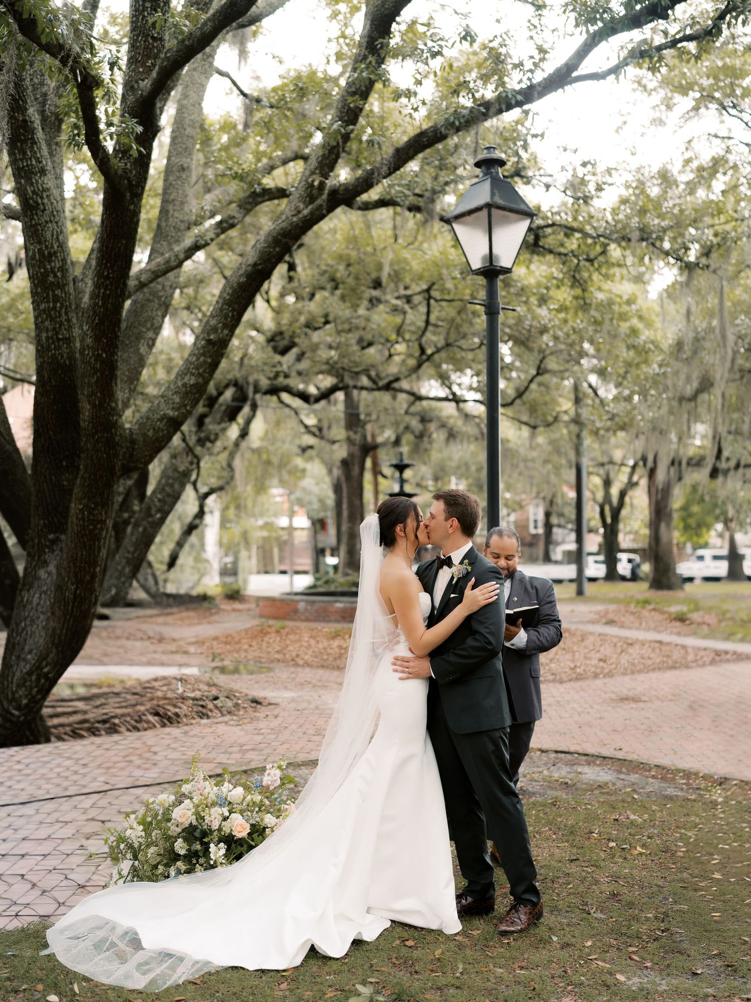 A romantic wedding ceremony takes place under majestic oak trees with hanging moss.