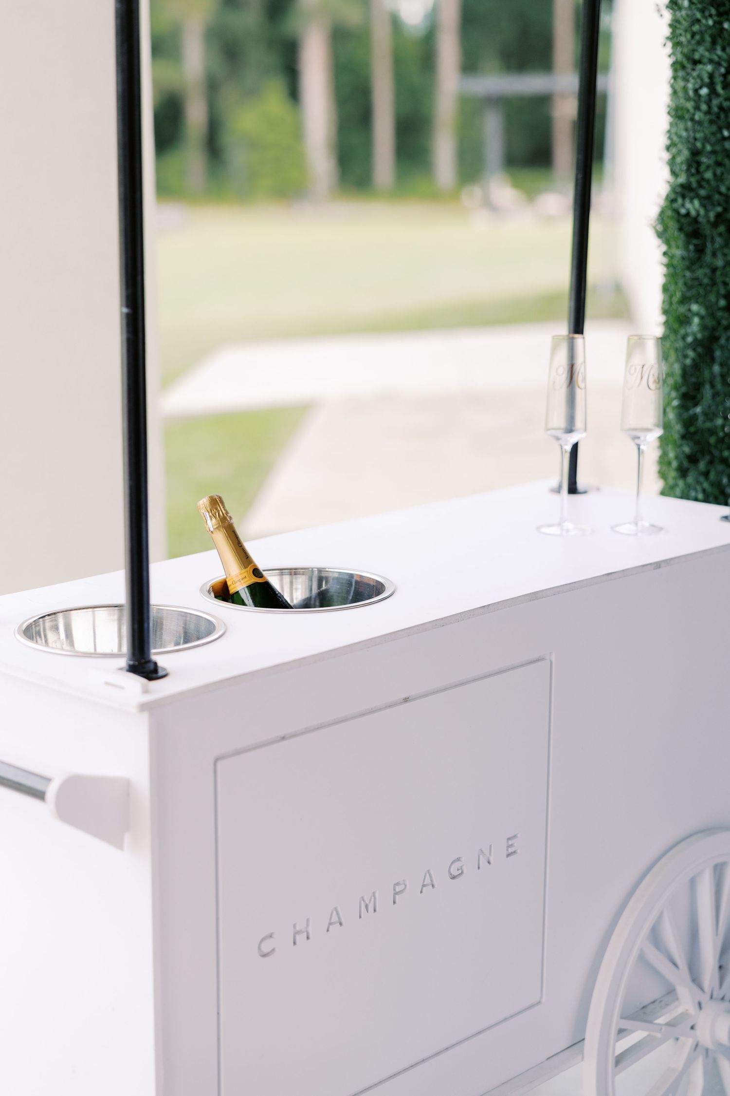 White champagne cart with built-in ice buckets at elegant wedding reception.