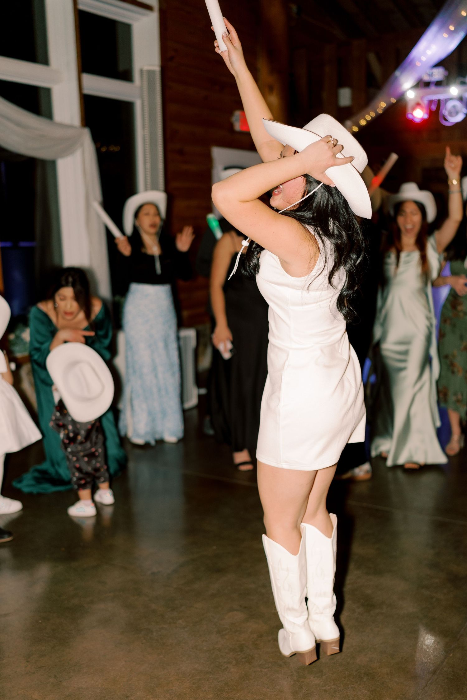 Dancers in white outfits performing energetic moves on a dark dance floor.