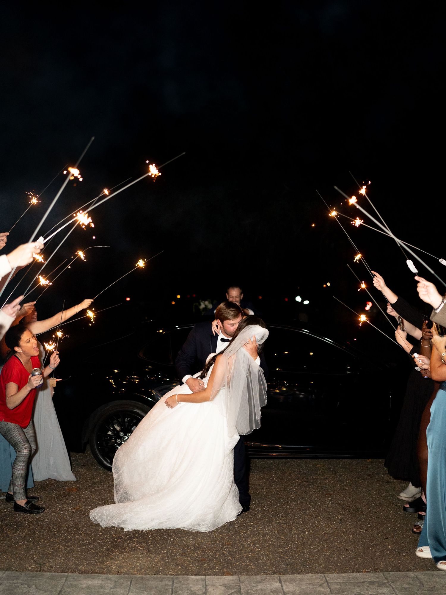 Wedding guests holding sparklers during an evening celebration outdoors.