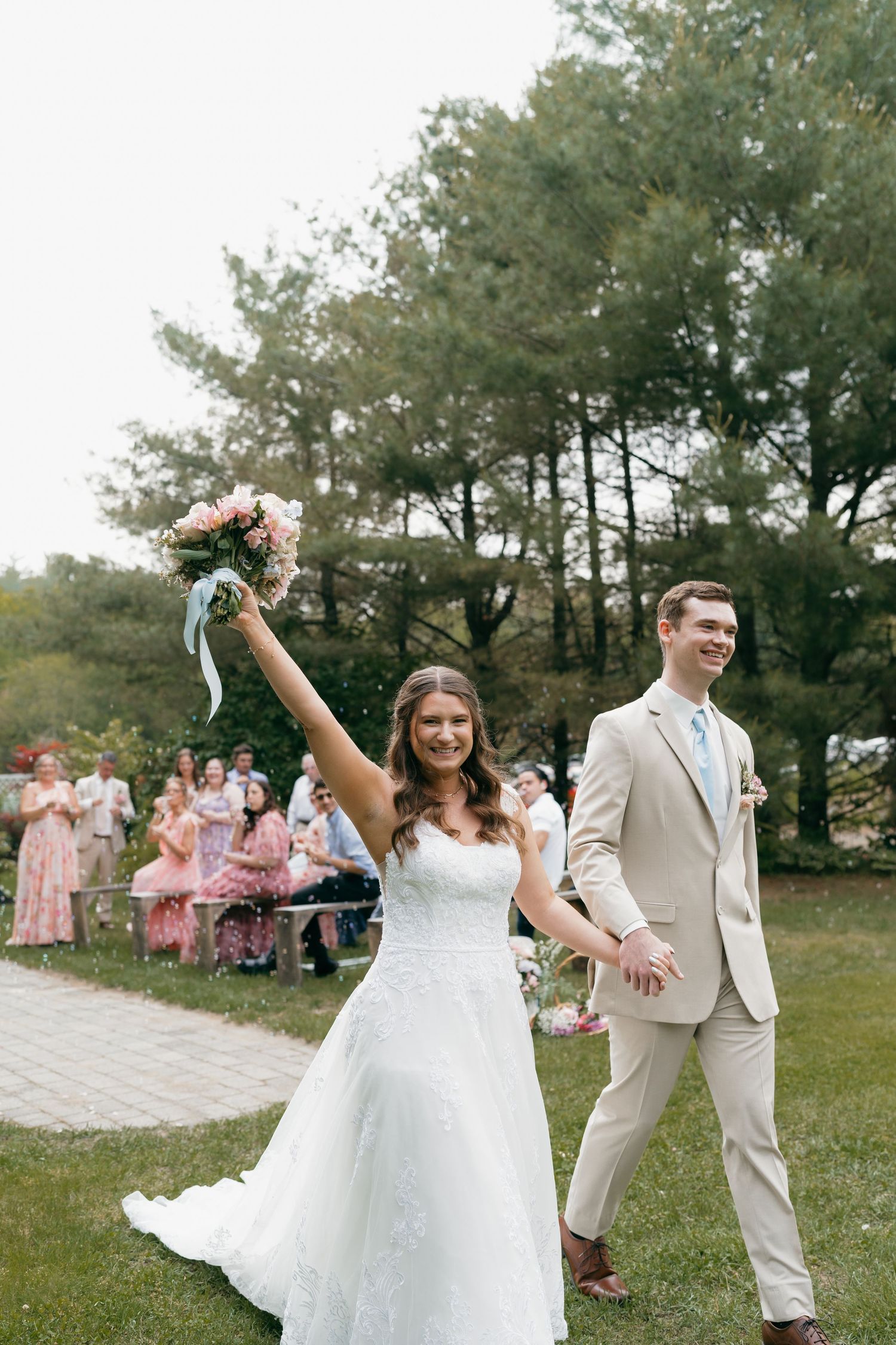 Wedding celebration in an outdoor garden setting with guests in pink dresses.