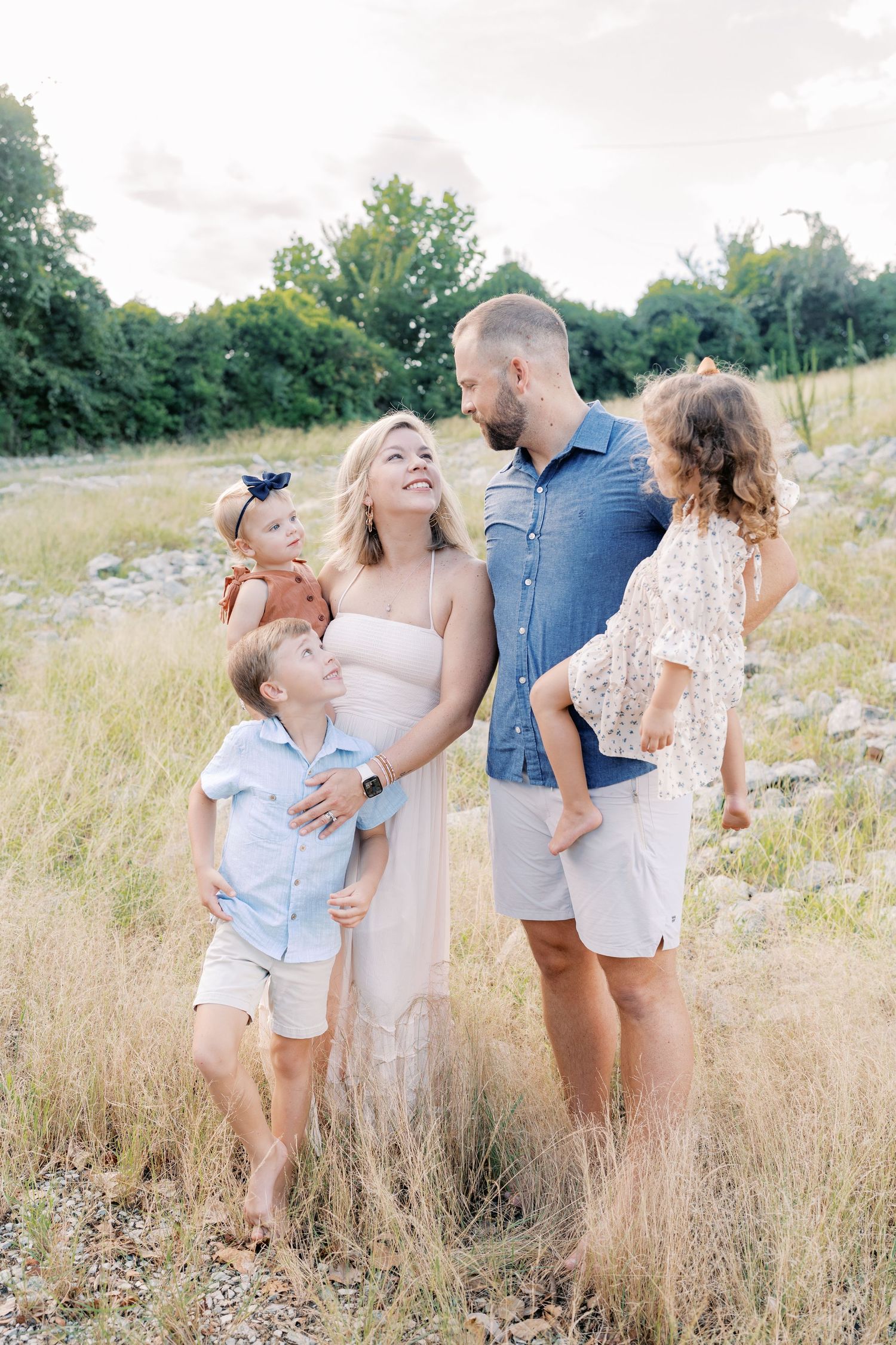 A family shares joyful laughter together in a sunlit meadow.