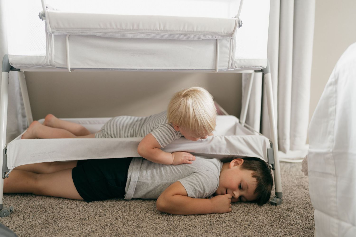 Peaceful resting figures lying on carpet beside white curtains.