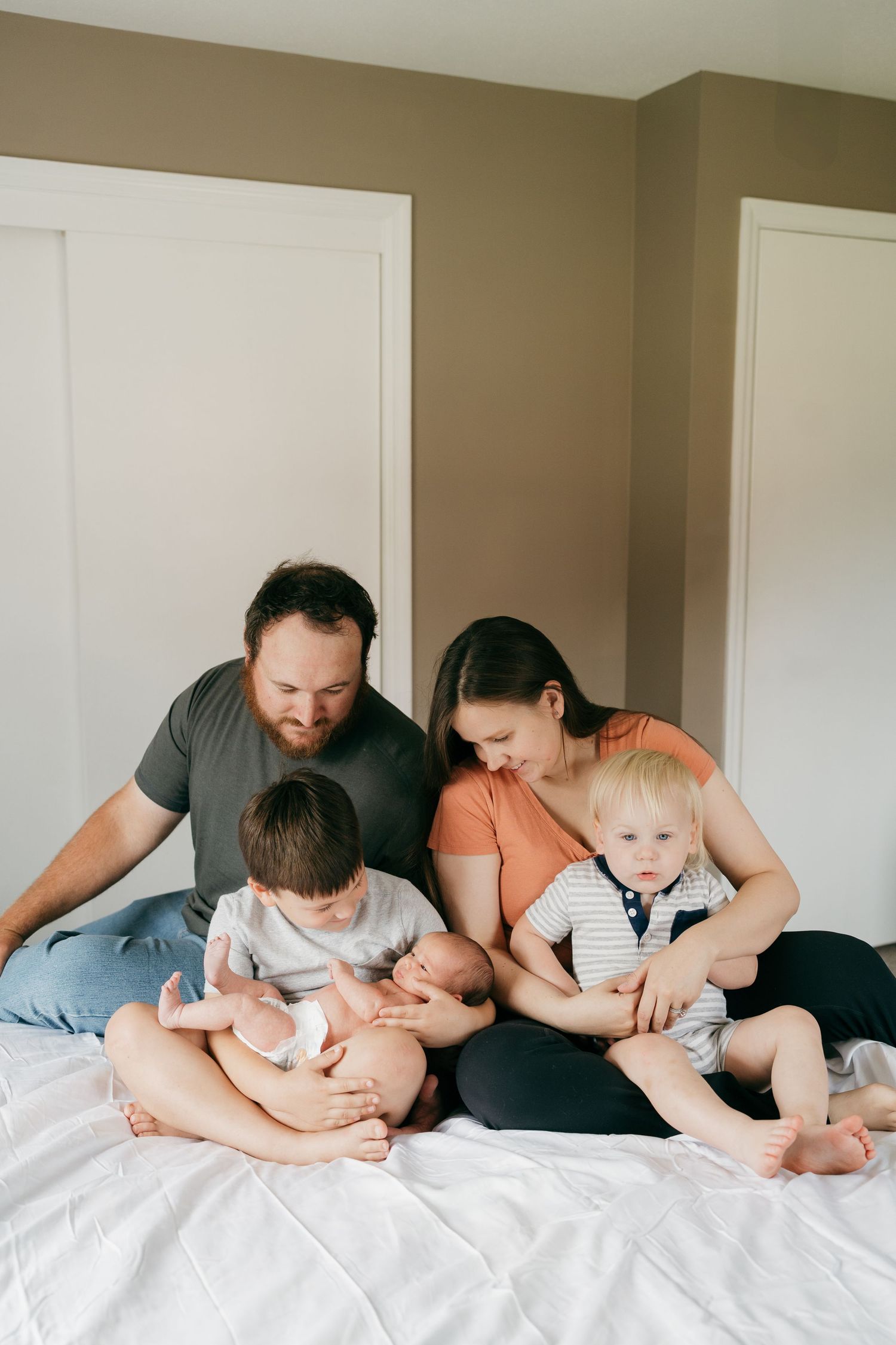 Family sharing intimate bonding moments together on bed during lifestyle photo session.
