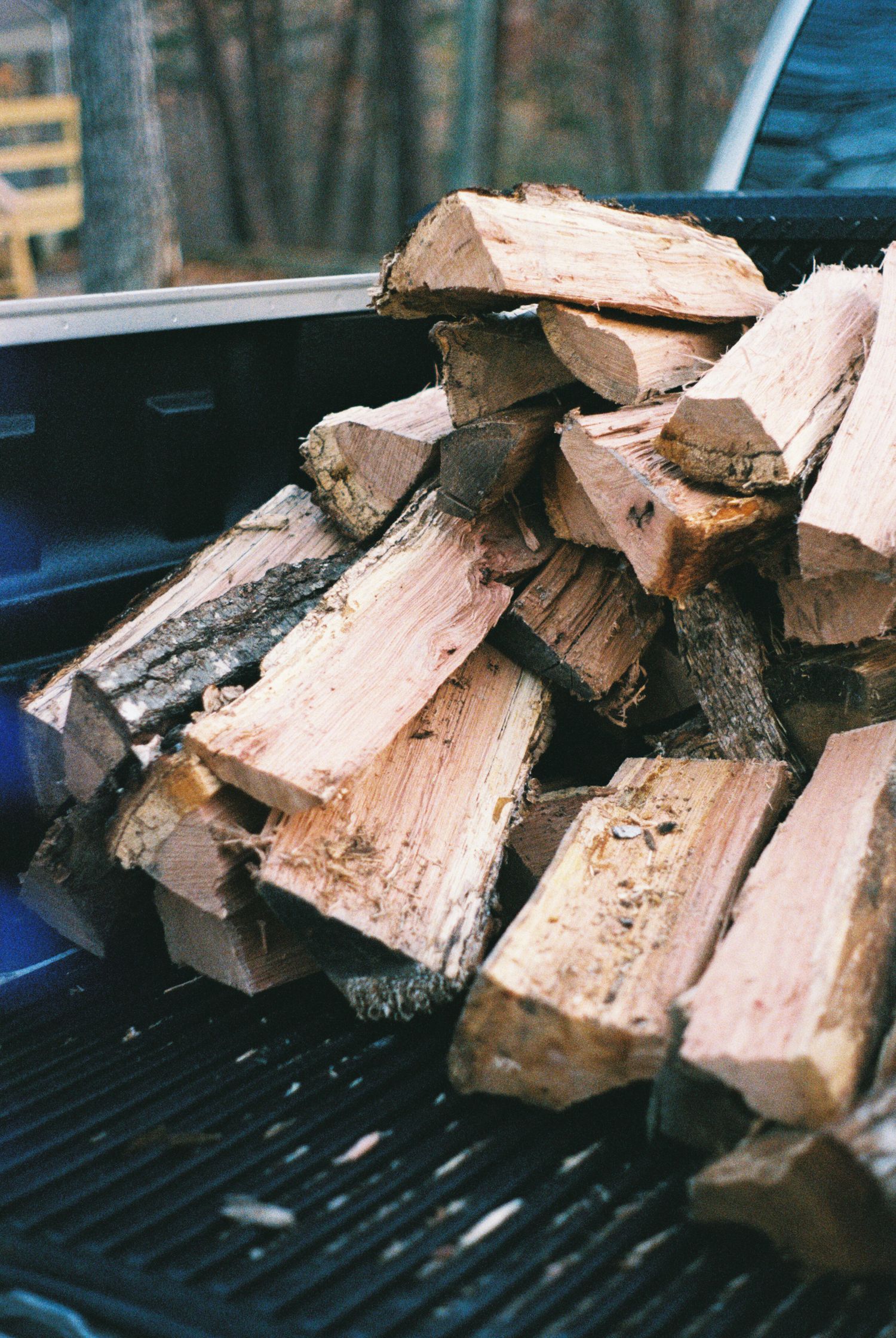 Stack of split firewood logs arranged on a dark grill or barbecue surface.