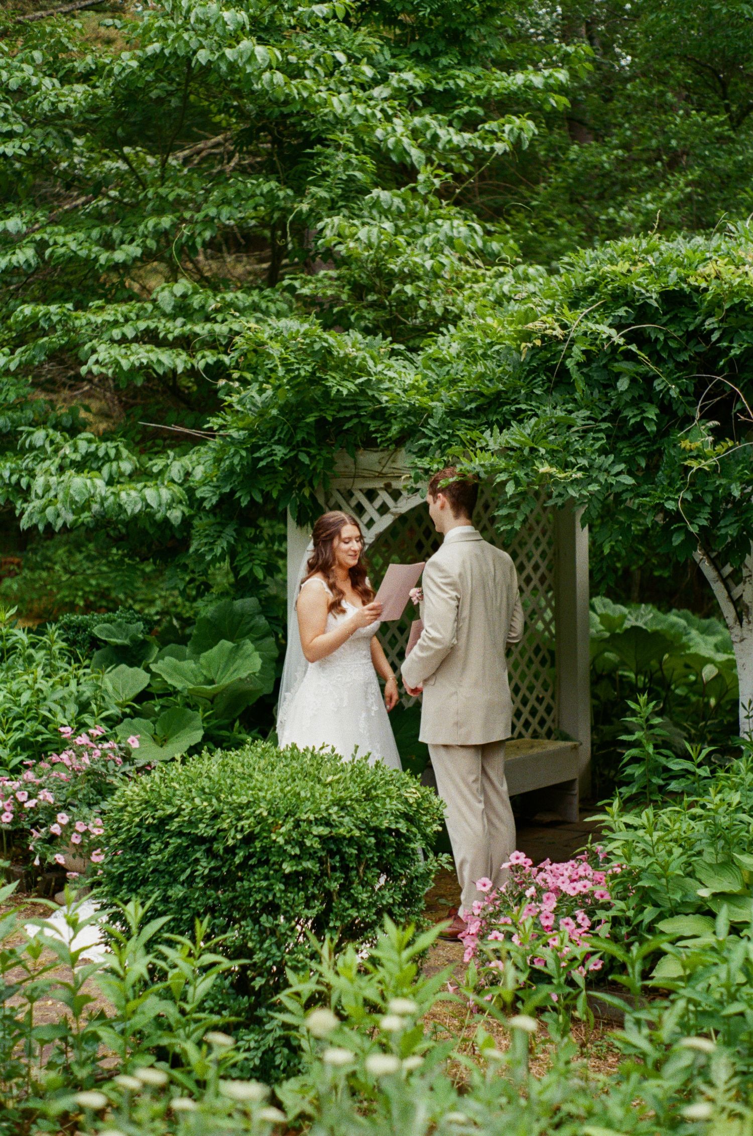 A wedding couple shares an intimate moment in a lush garden setting surrounded by greenery.
