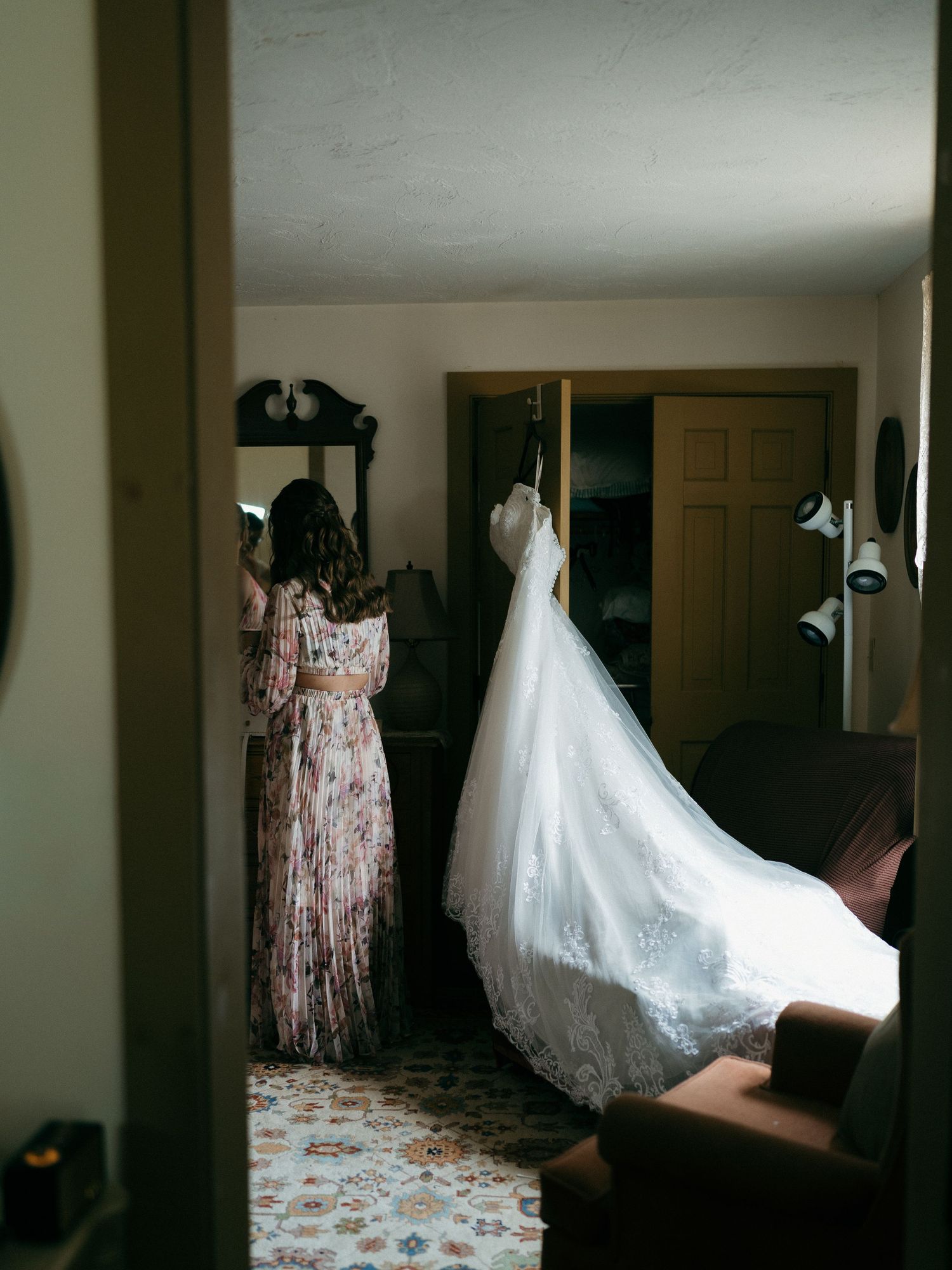 Wedding dresses and floral bridesmaid gowns hanging in a dimly lit room.
