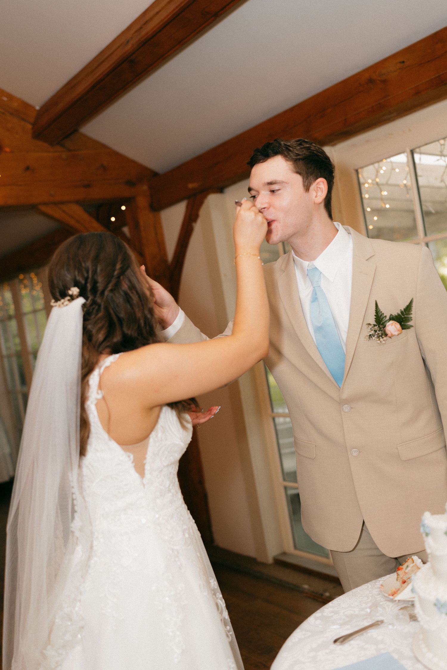 Couple shares their first dance in an elegant barn venue with wooden beams.
