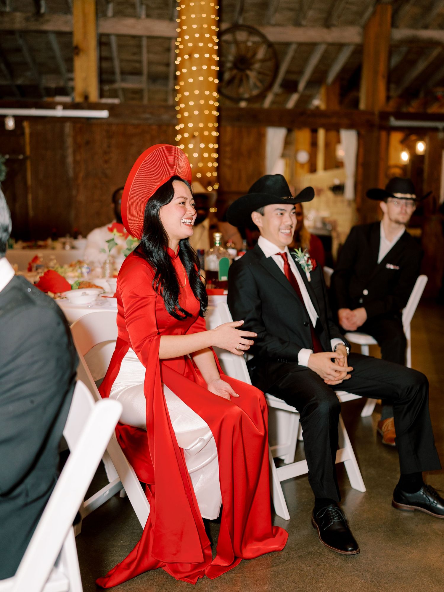 Wedding reception guests dancing and celebrating in formal attire and red capes.