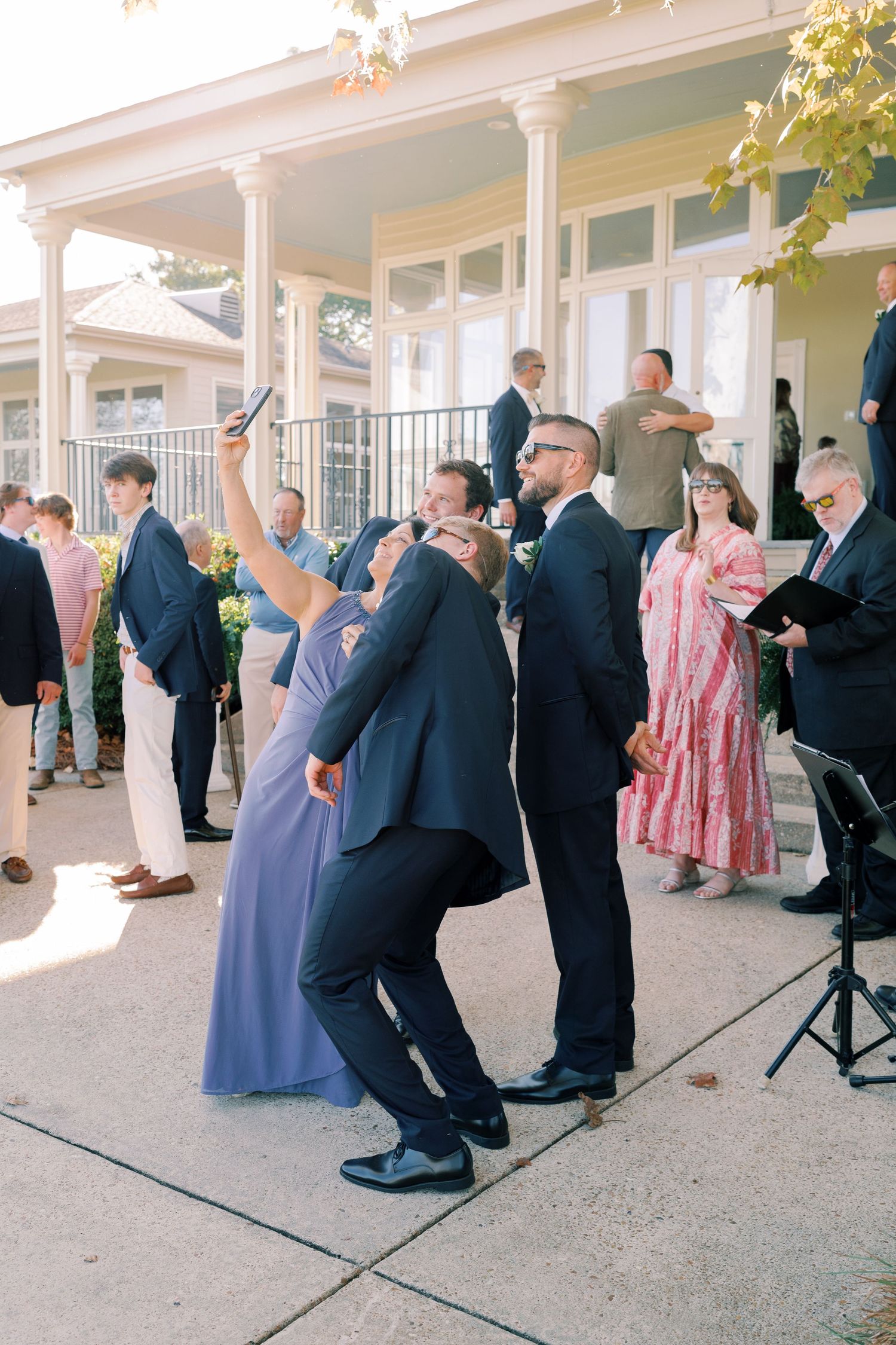 Wedding guests dancing in formal attire on an outdoor patio during a reception celebration.