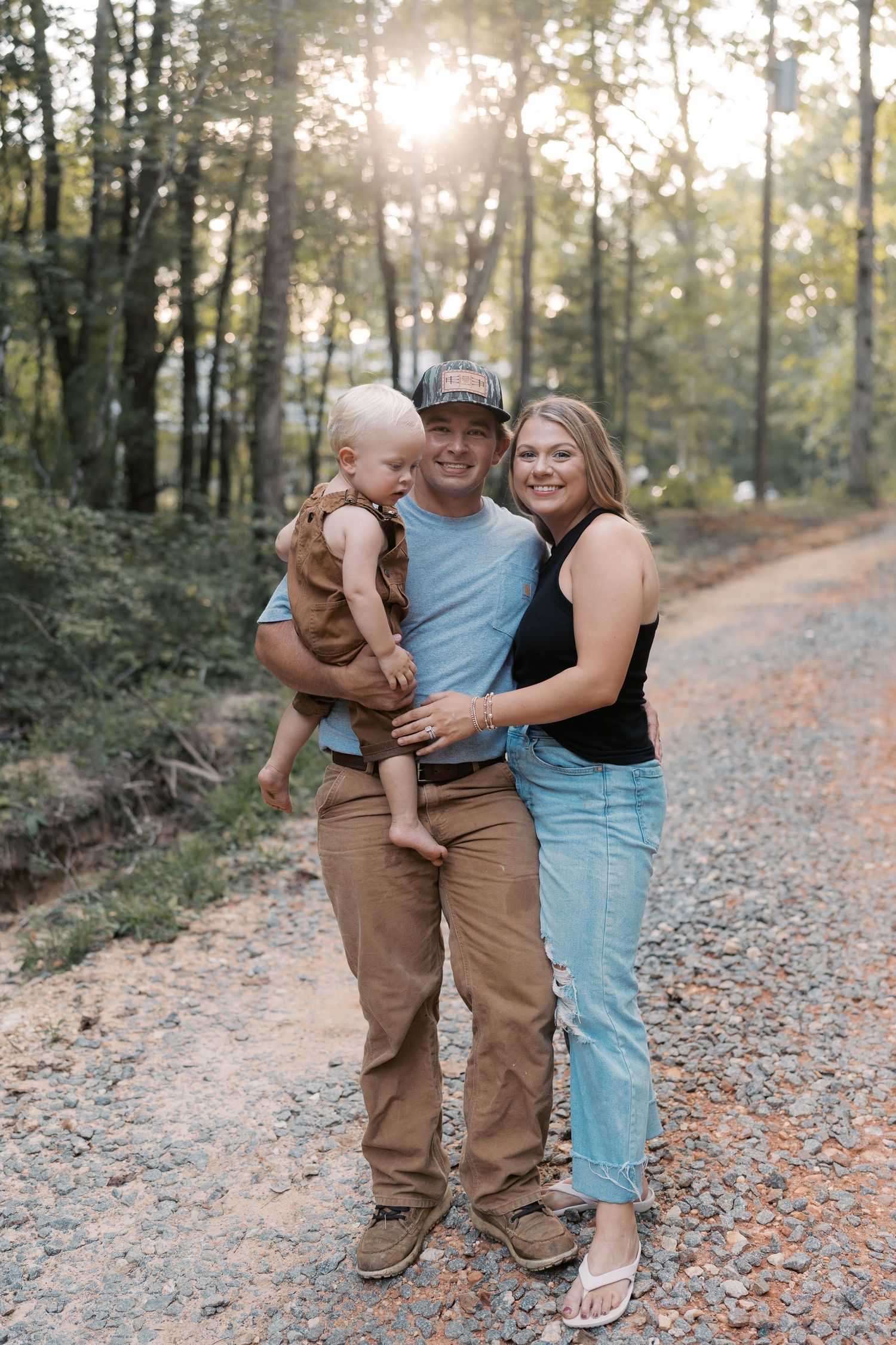 A family shares intimate moments together on a forest path during sunset.