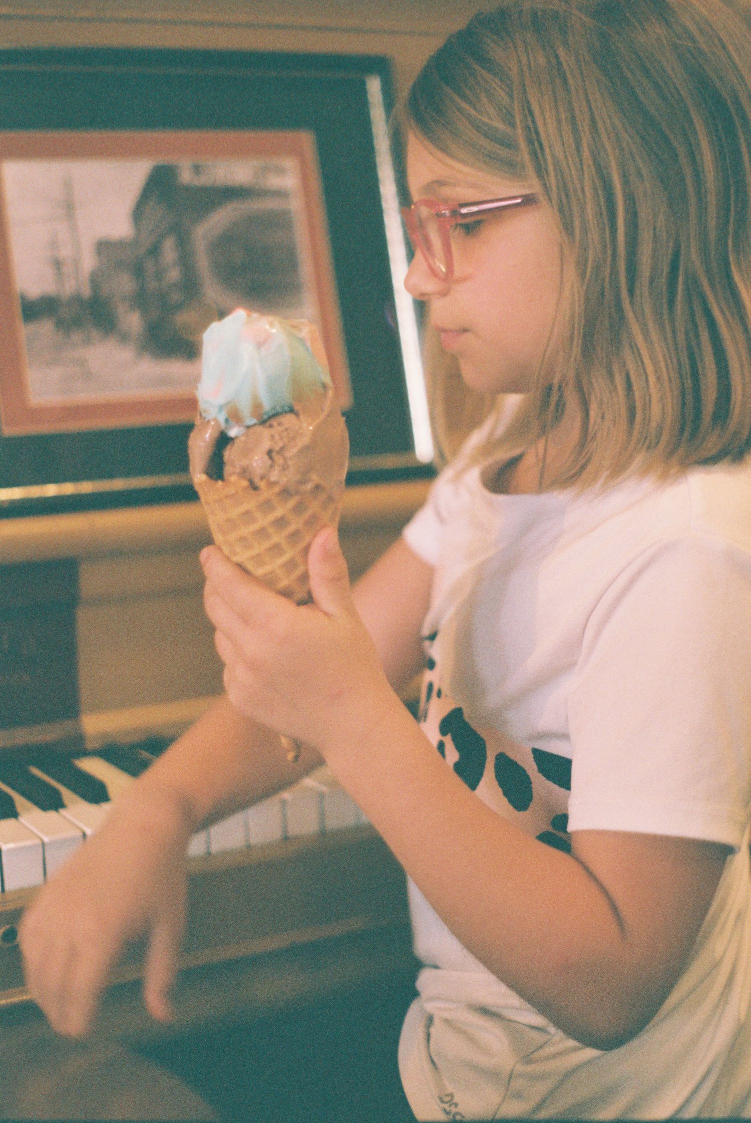 Someone enjoying a vanilla ice cream cone while sitting at a piano.