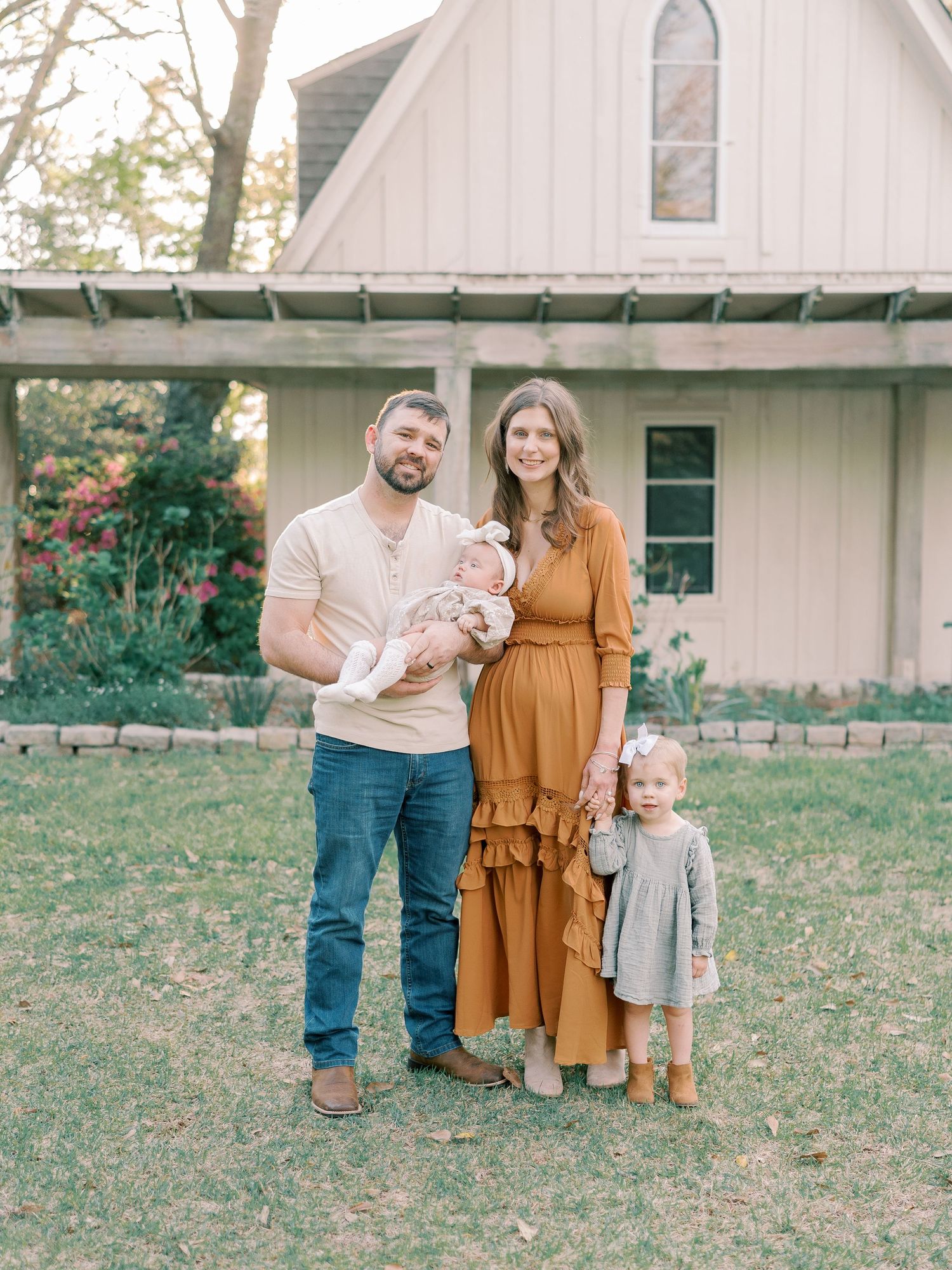 Family in coordinated autumn outfits standing together outside white church building.