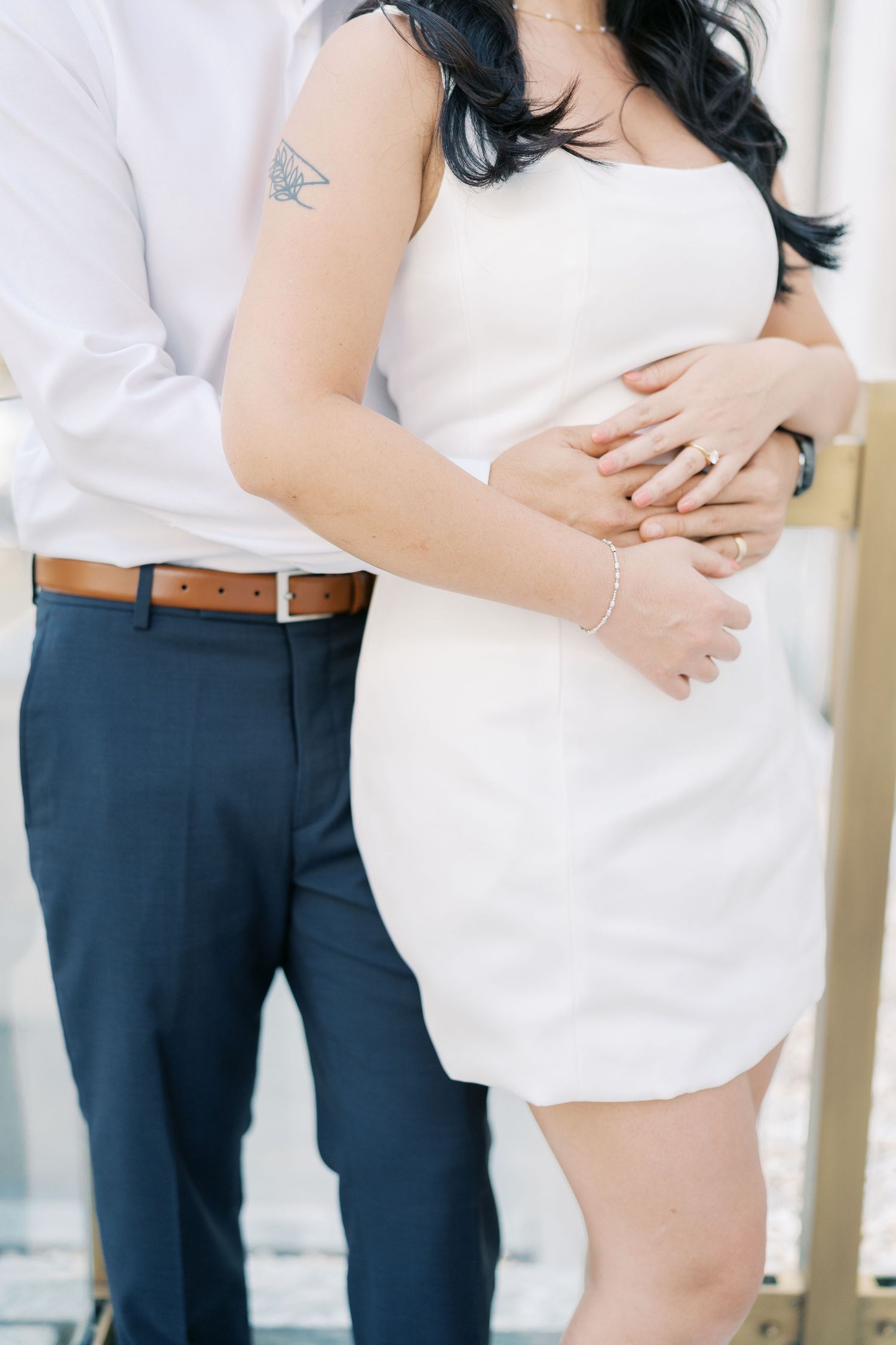 Close-up details of a couple in coordinating white and navy outfits during an outdoor photoshoot.