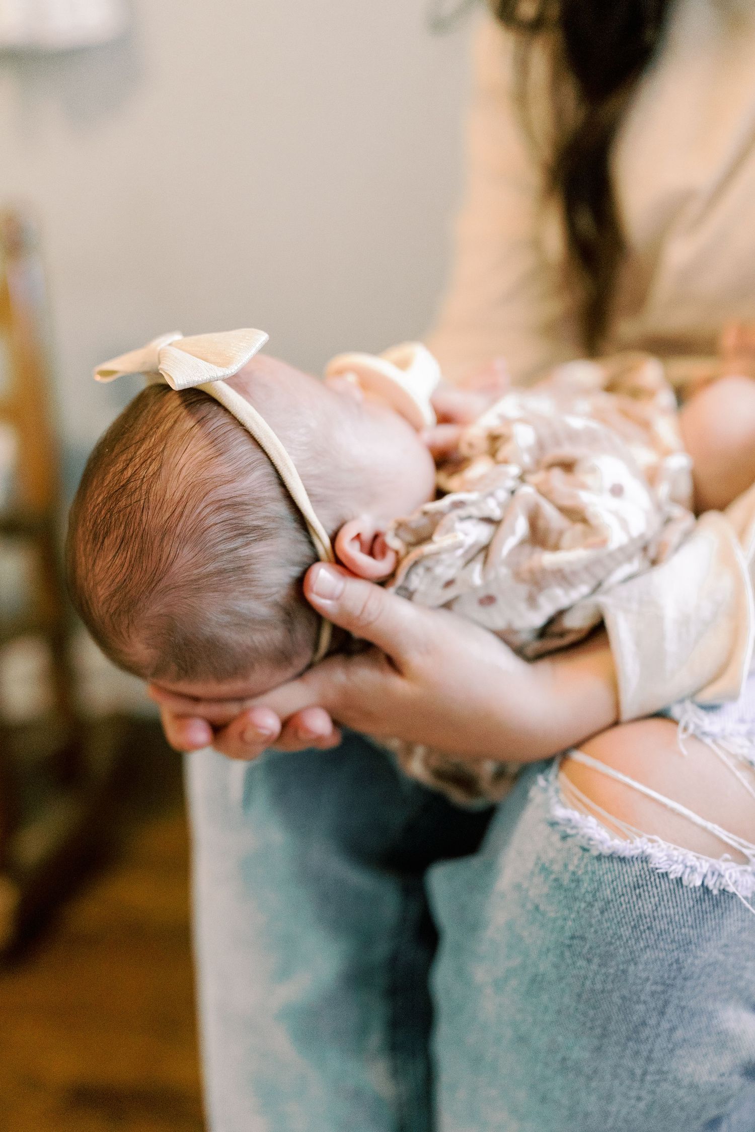 Close-up shots of a sleeping newborn being gently cradled in denim-clad arms.