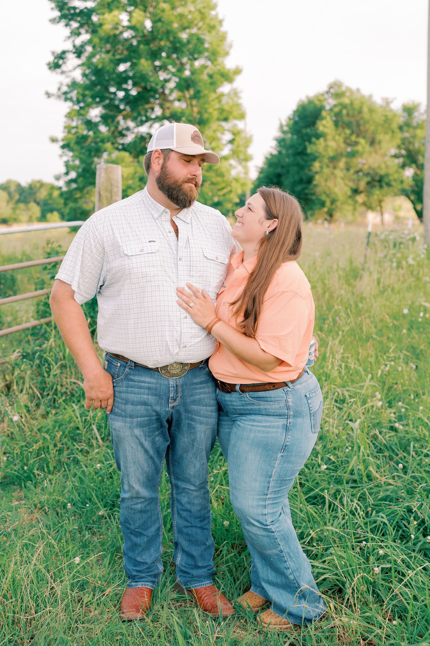 Couple in casual attire sharing an intimate moment by rustic fence.