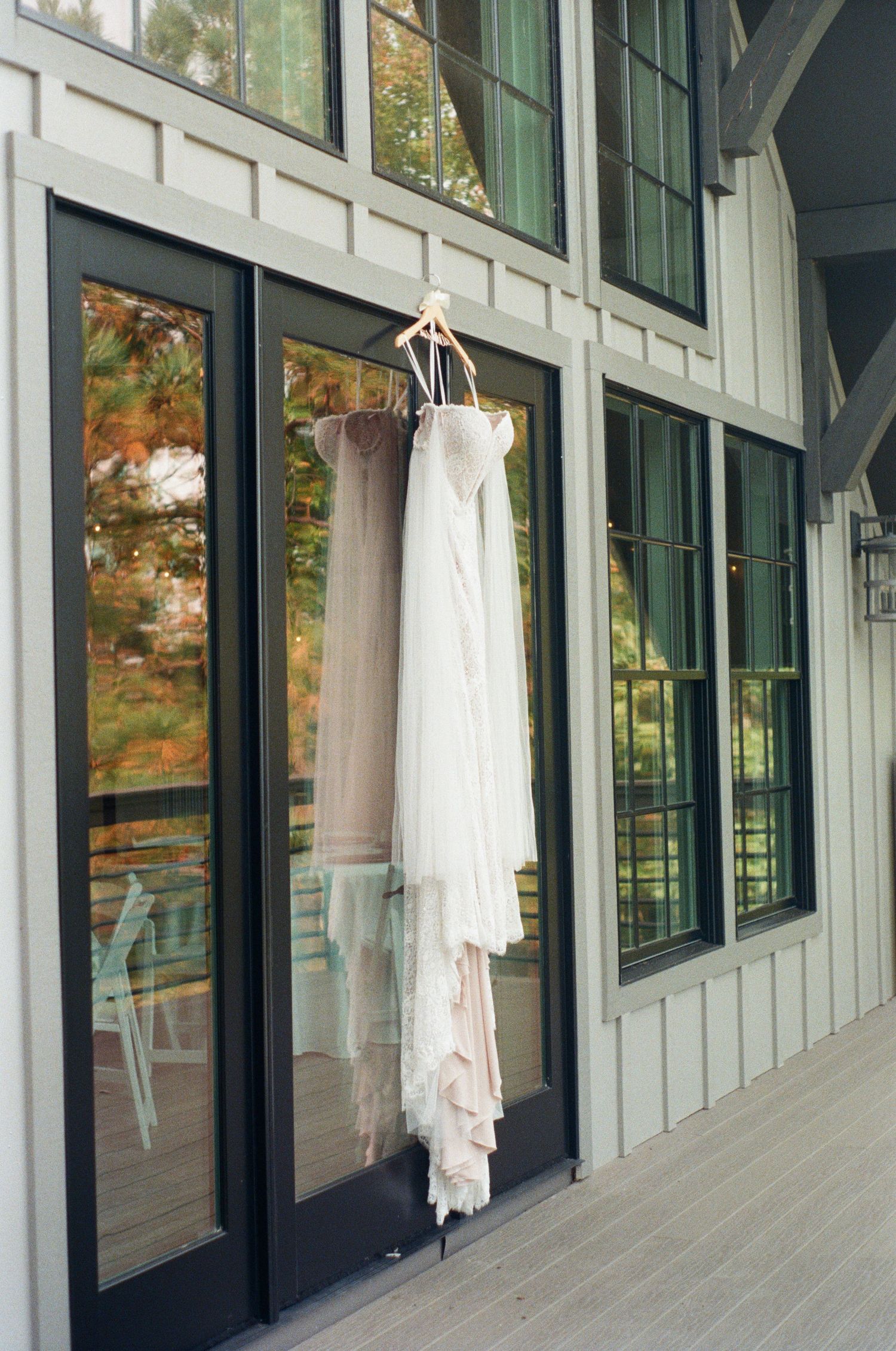 White wedding dresses hanging in a row along windows in a bright hallway.