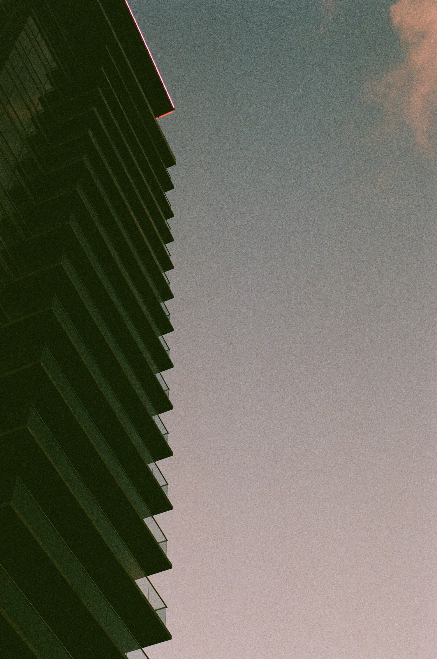 Angular architectural detail of a building with geometric shadows against blue sky.