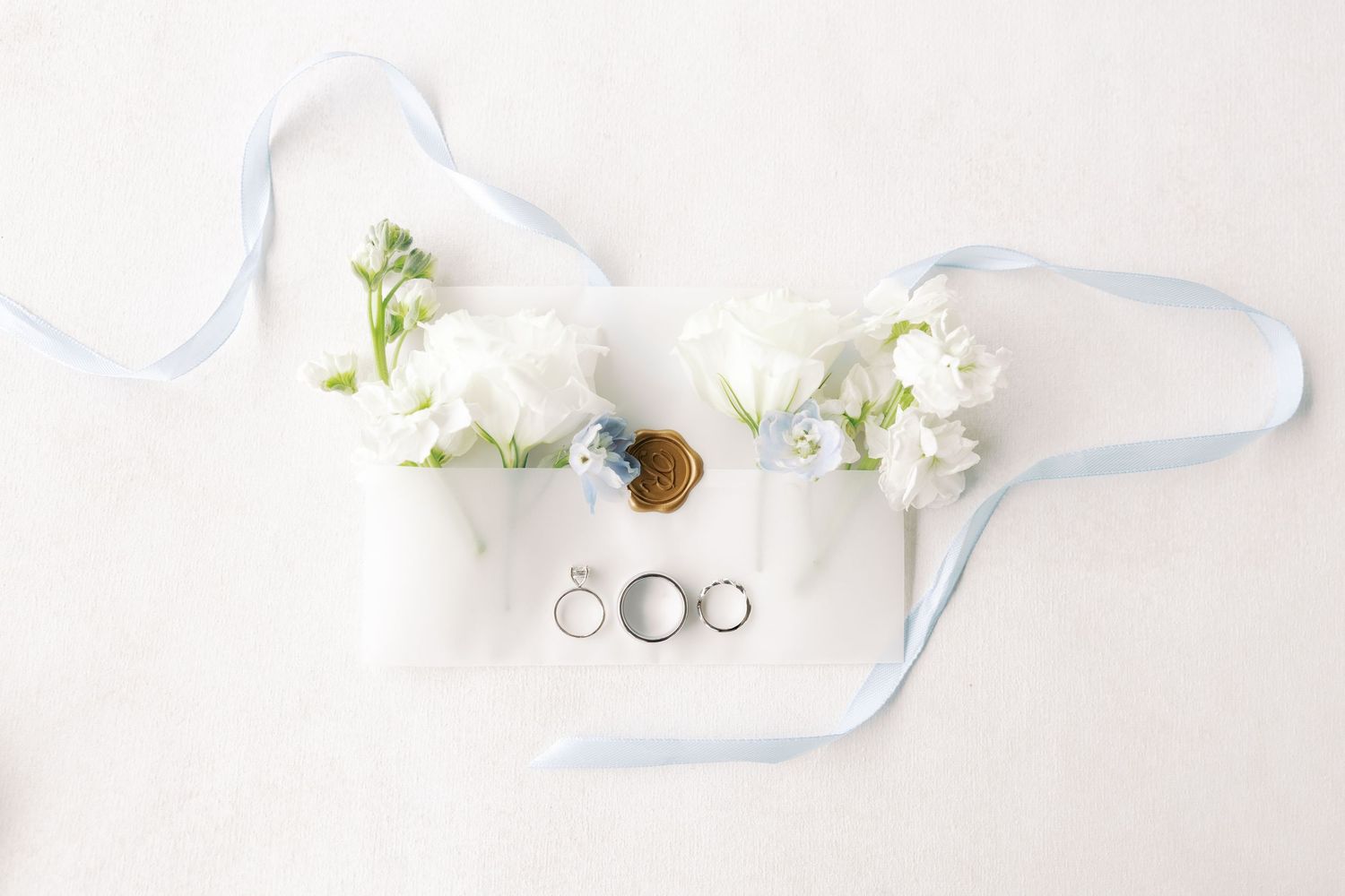 Delicate white floral arrangements with blue ribbons laid out on a light background.