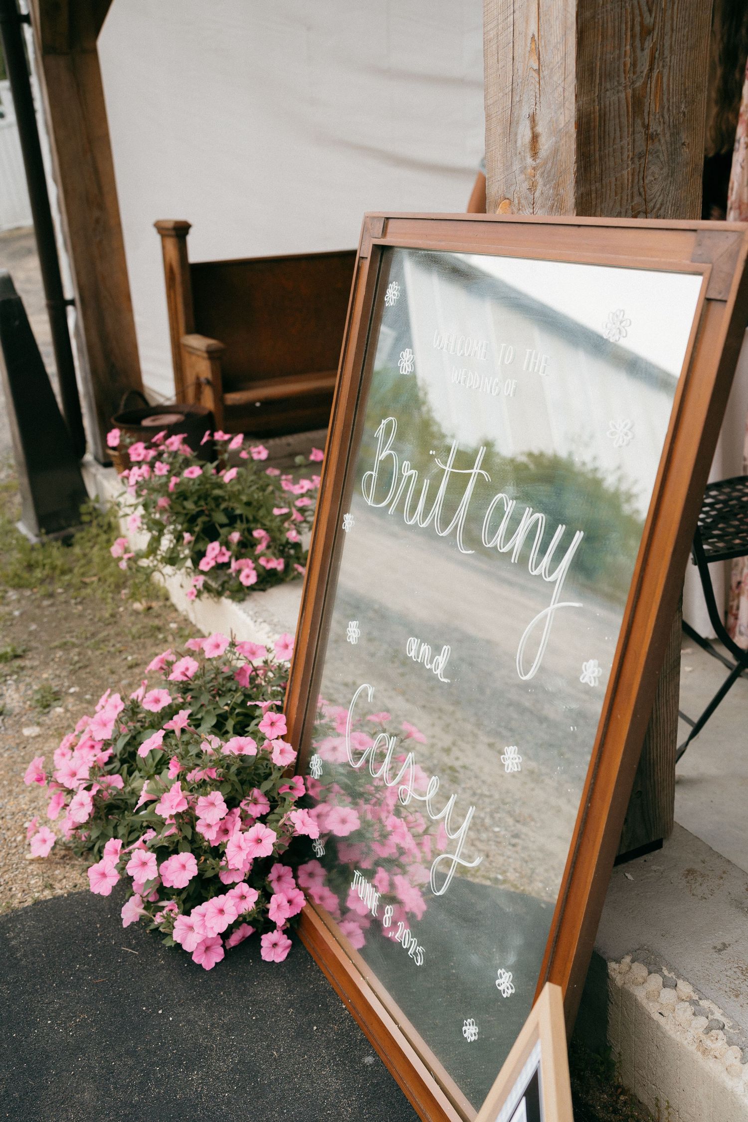 Rustic wooden framed mirror decorated with pink flowers and handwritten text.